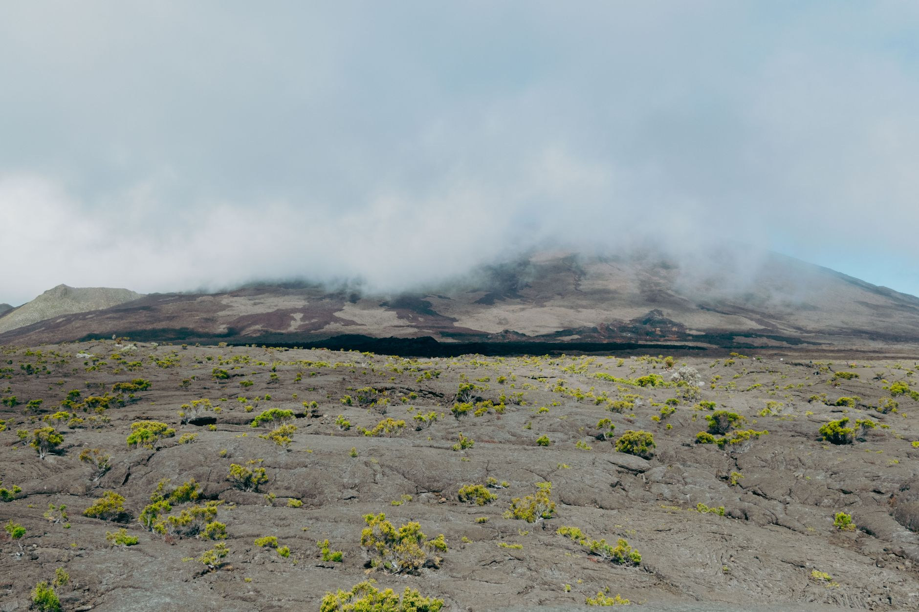 Rugged volcanic terrain and lava flow fields of Piton de la Fournaise under mountain clouds on La Réunion