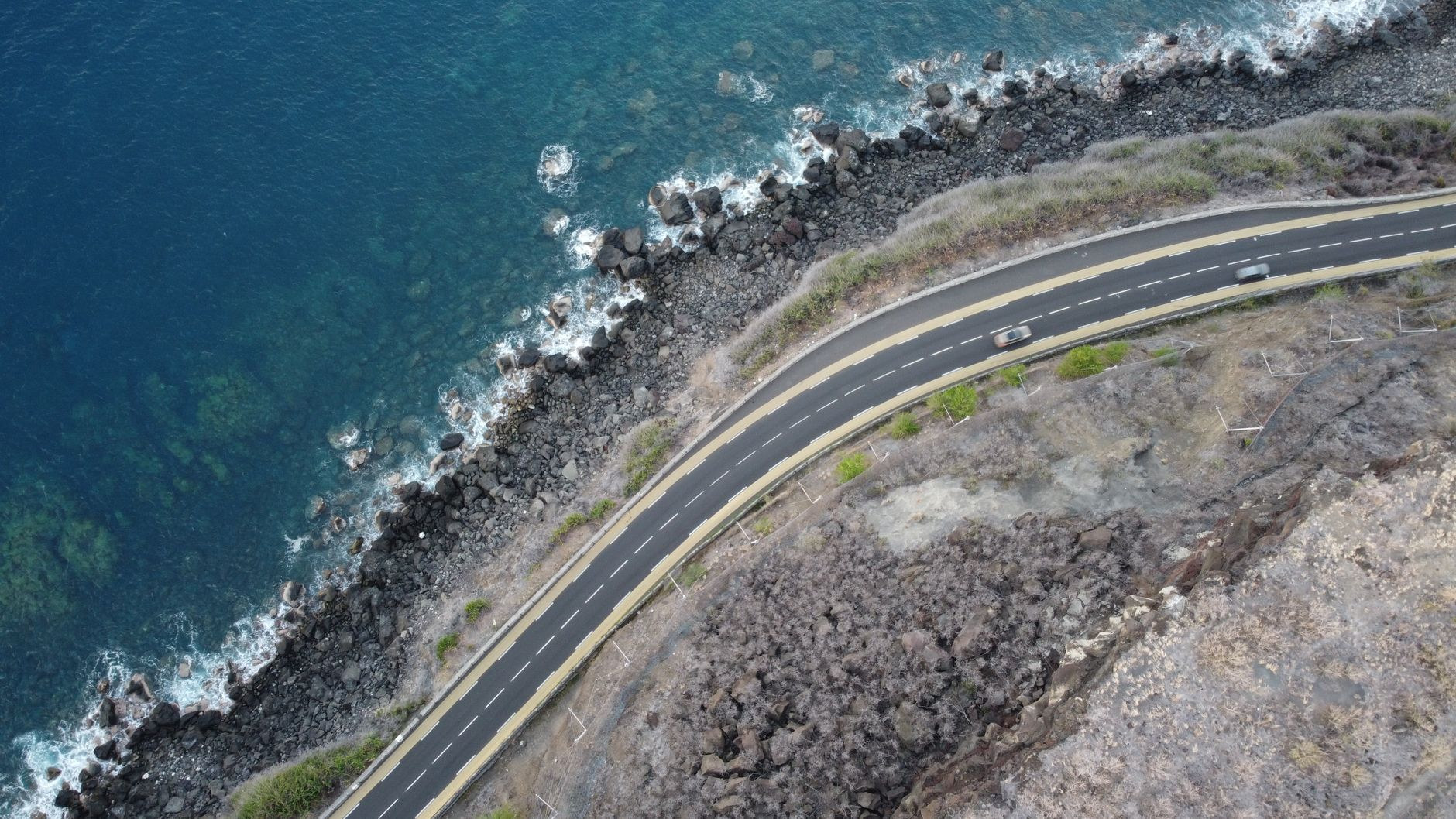Aerial view of the coastal highway spanning rugged shoreline cliffs beside the Indian Ocean in La Réunion