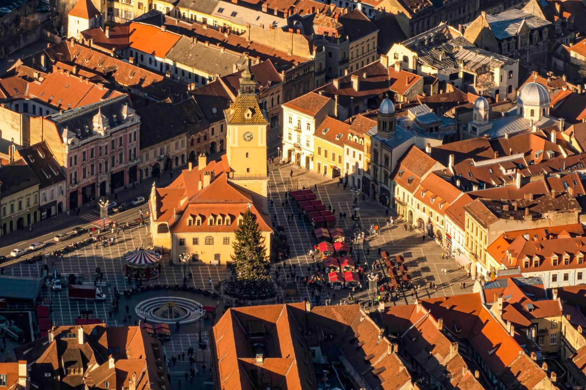 Colorful baroque merchant houses around Brasov Council Square with Mount Tampa rising behind the historic Black Church