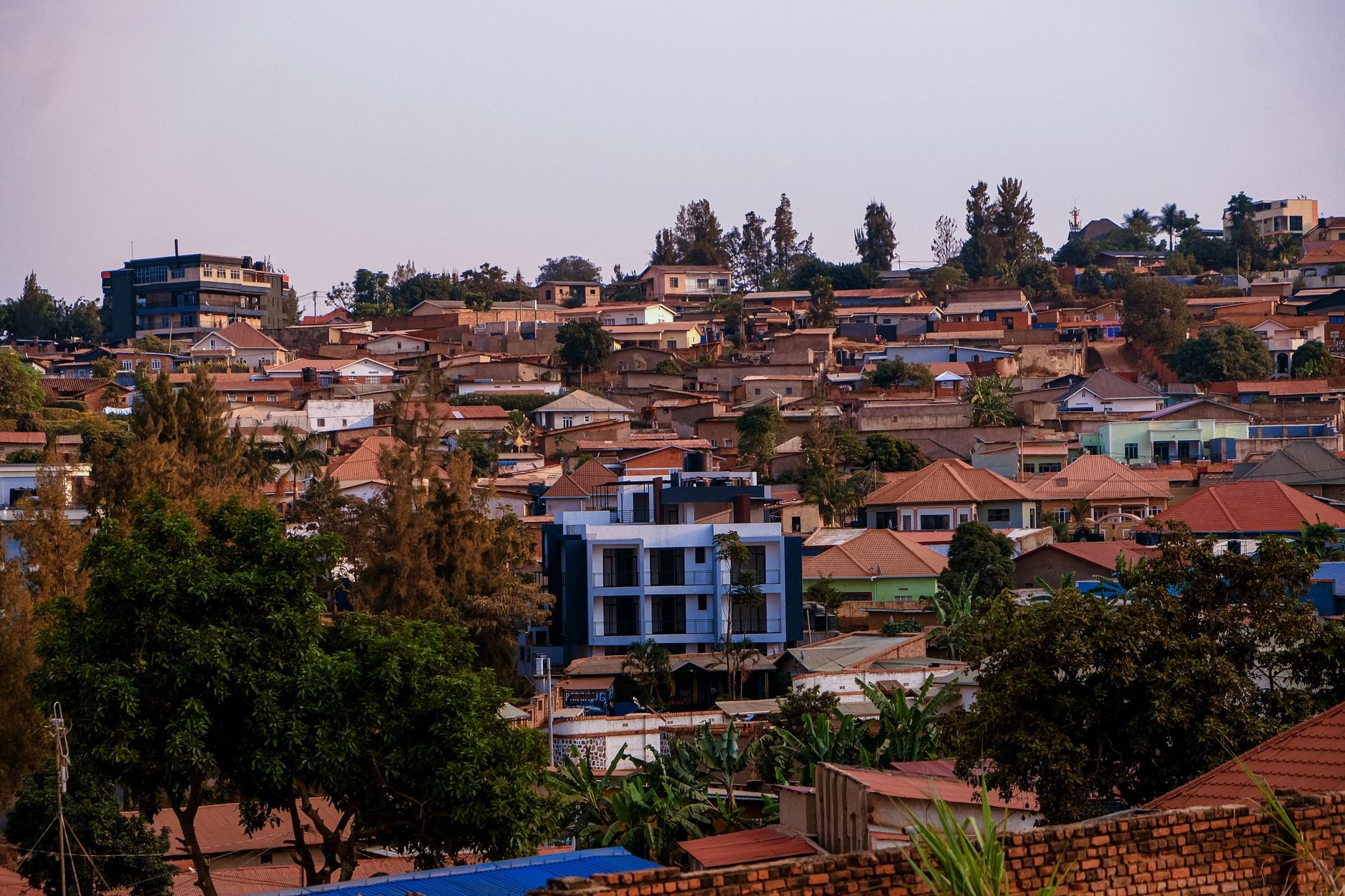 Clean modern paved boulevards and contemporary architecture spread across green terraced hills in Kigali