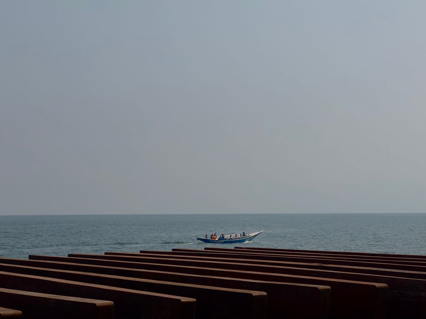 Traditional three-hulled wooden fishing boats resting near palm trees along the calm blue waters of Lake Kivu