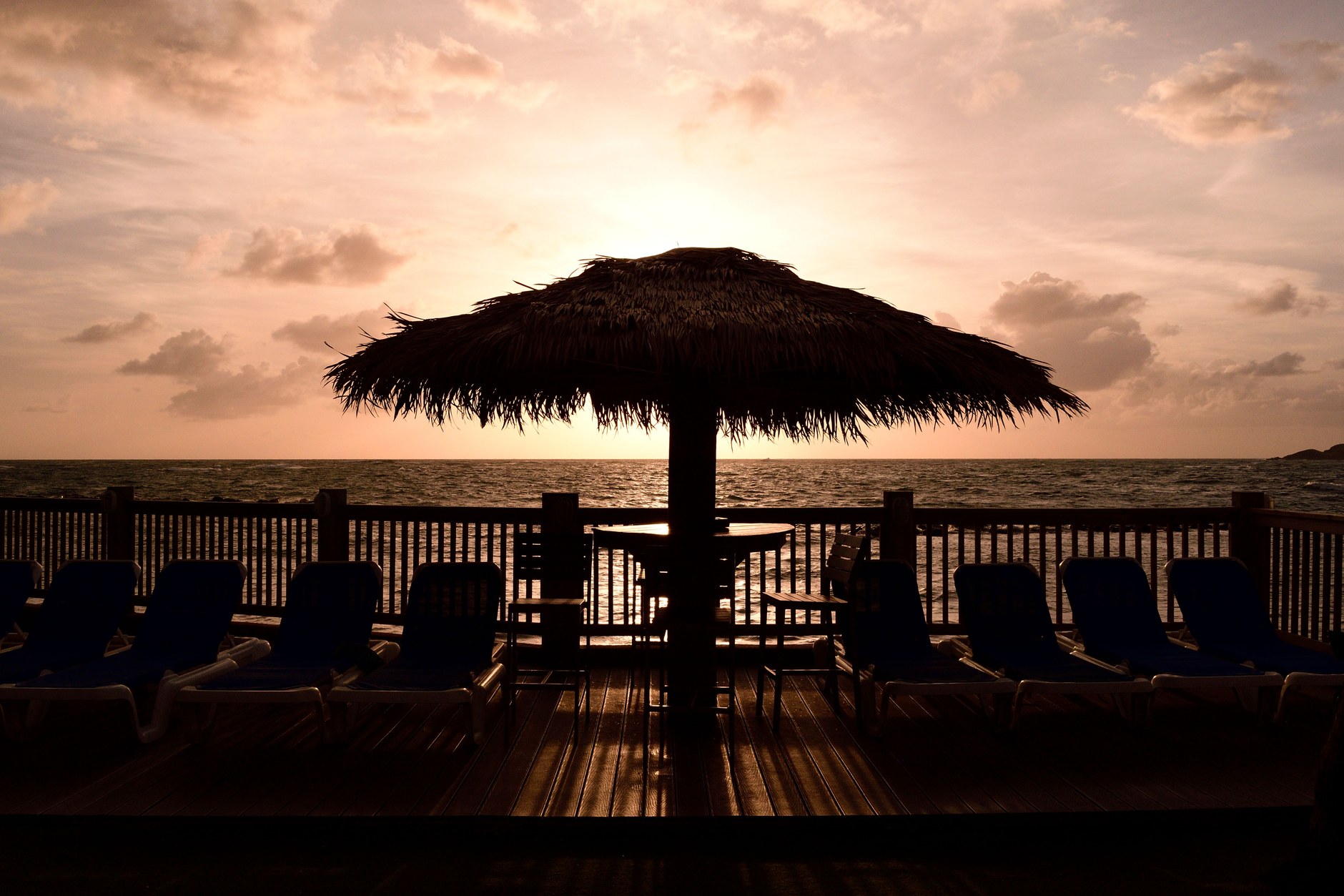 Silhouette of a thatched beach parasol overlooking calm ocean water under evening skies in Saint Lucia