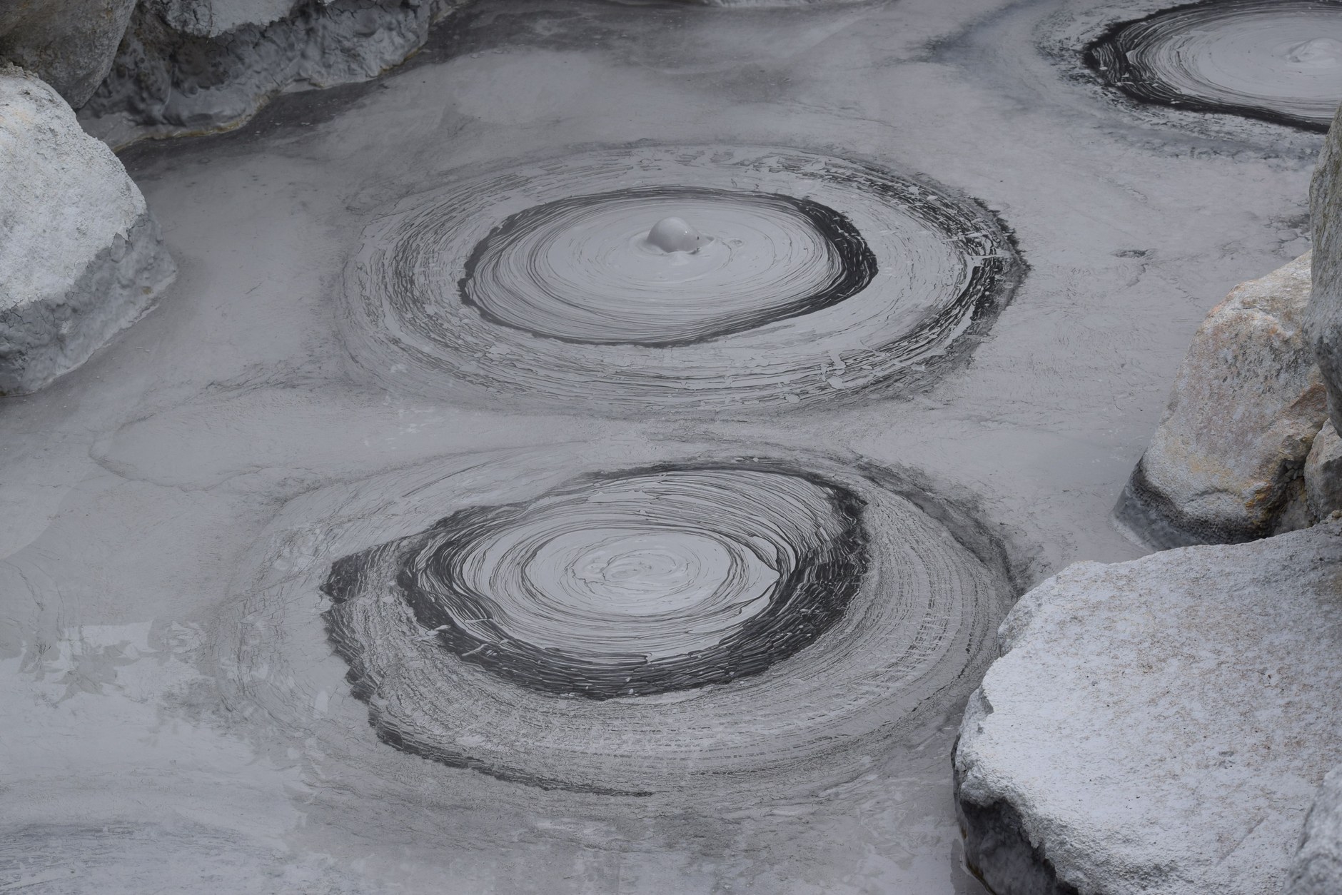 Mineral-rich volcanic mud pools with geothermal steam and mineral sediment in a volcanic caldera