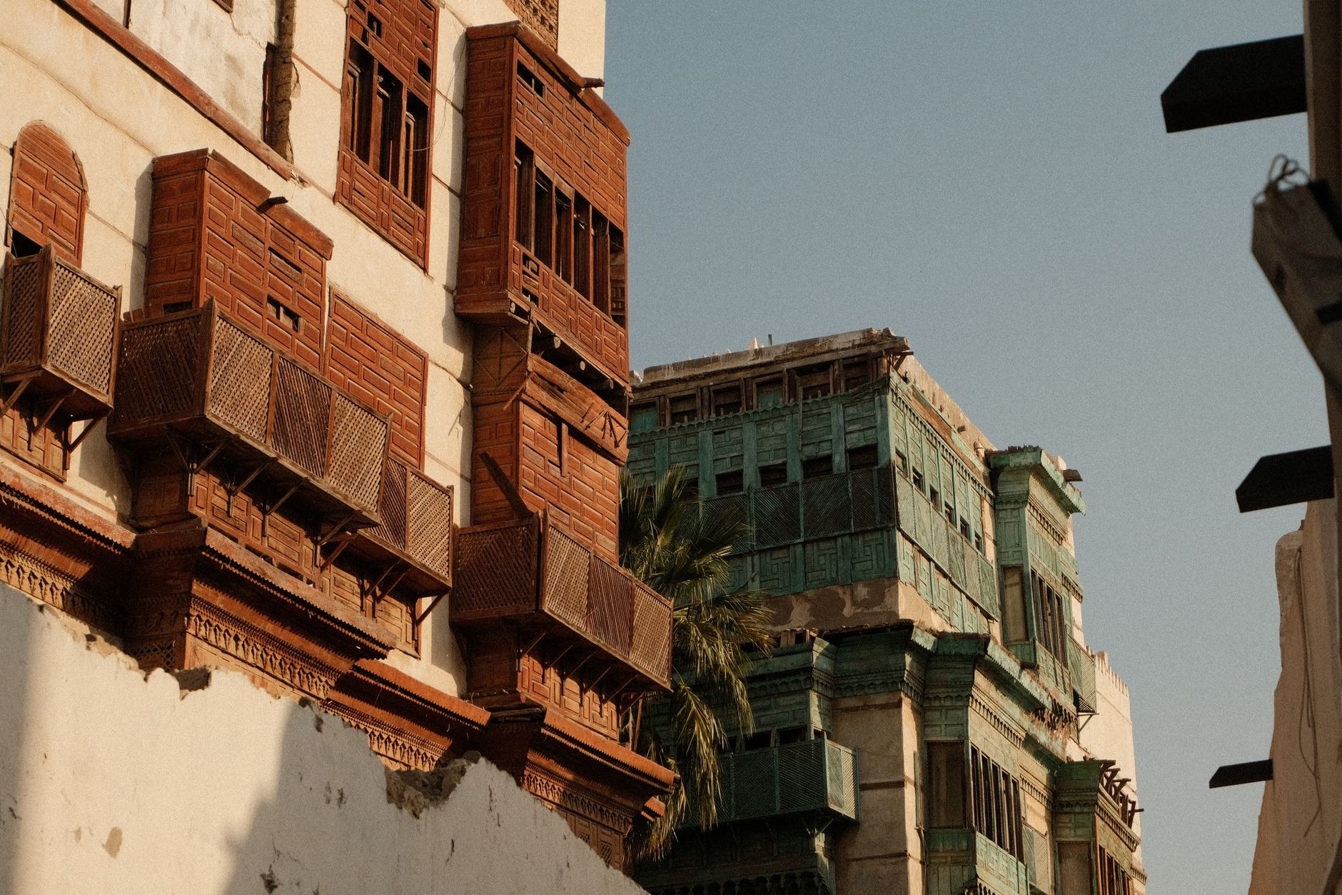 Traditional multi-story coral-stone merchant houses adorned with intricate dark wooden rawasheen window screens in Jeddah's historic Al-Balad