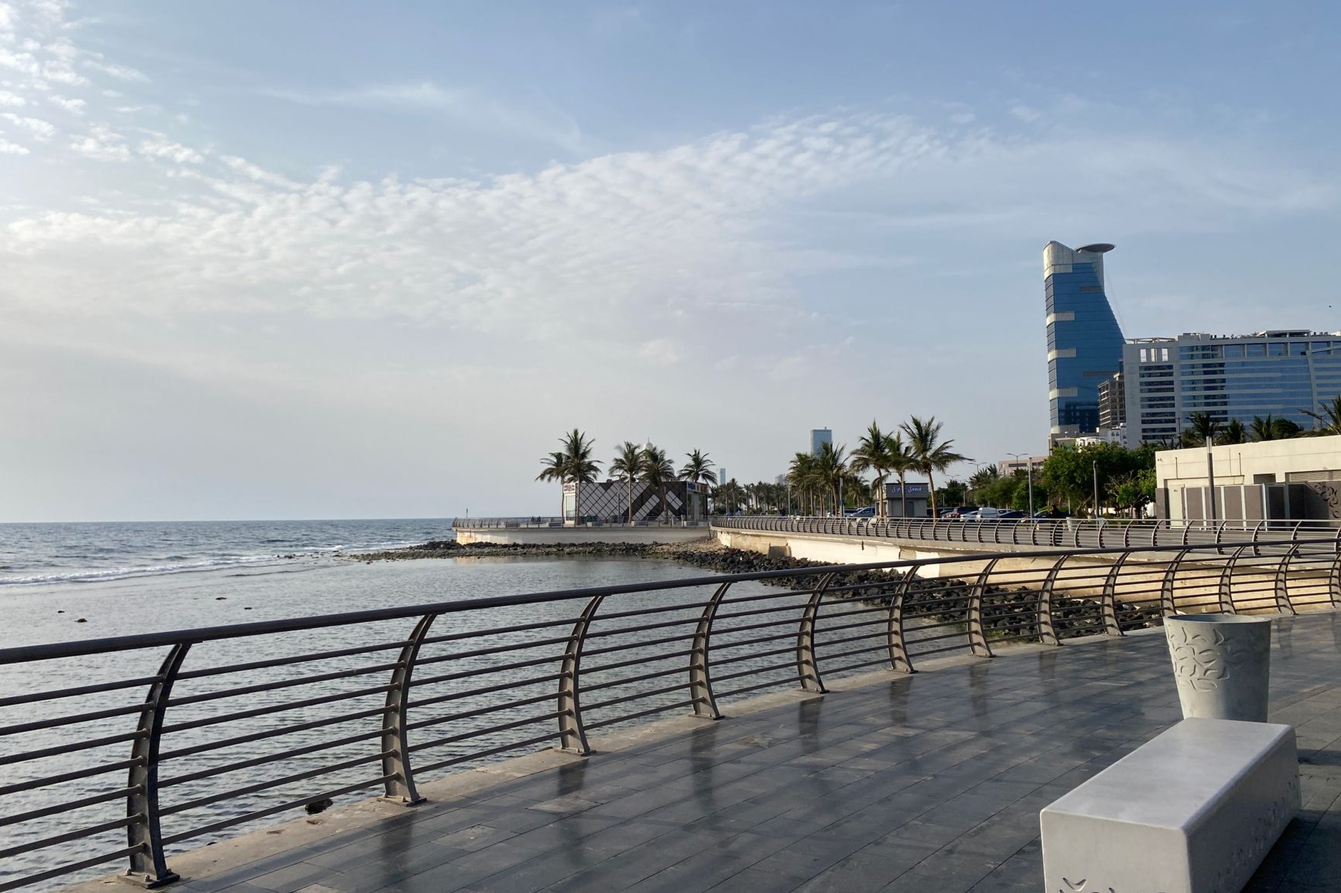 Palm-lined promenade of the Jeddah Corniche looking out across the sparkling blue waters of the Red Sea at twilight