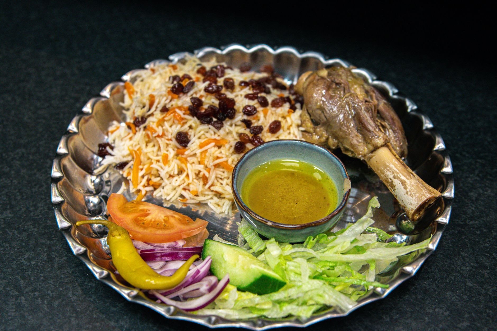 Traditional Saudi kabsa platter featuring spiced fragrant basmati rice topped with tender roasted lamb, toasted almonds, and golden raisins