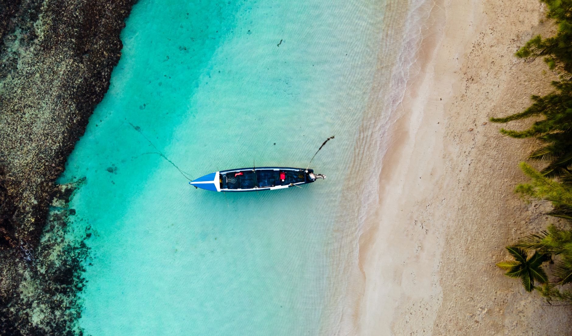 Colorfully painted wooden fishing pirogues with carved prows resting along the sandy beach at sunset in Senegal