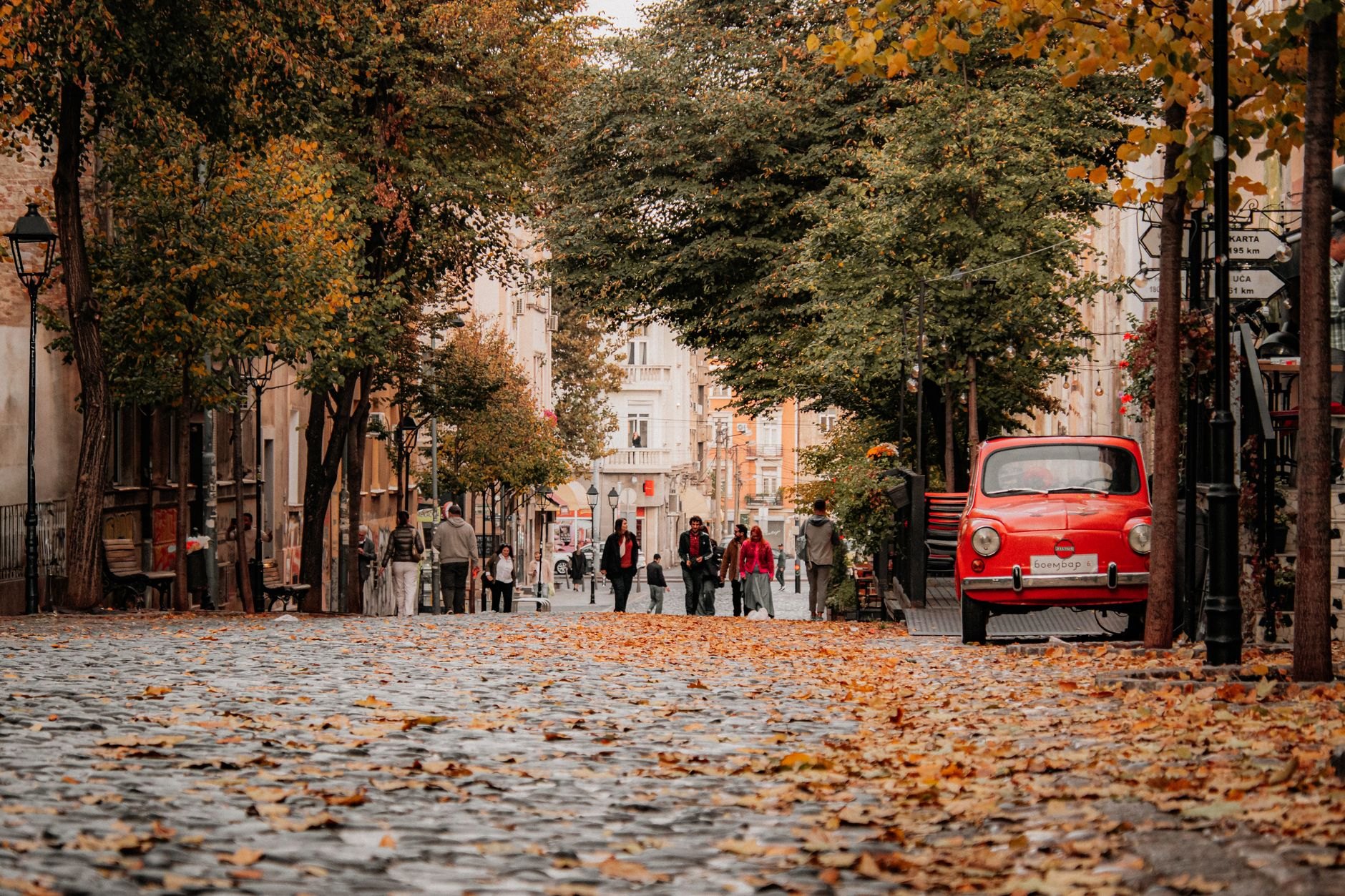 Curving cobblestone street lined with lantern-lit traditional Serbian kafanas and outdoor dining terraces in Skadarlija