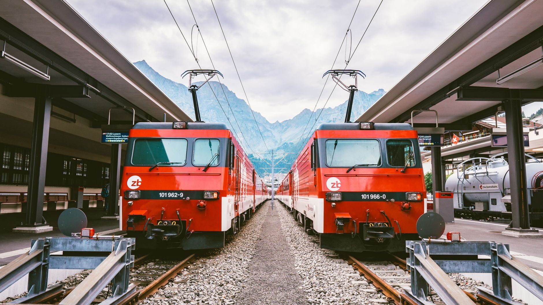 Red and white mountain passenger train winding through evergreen alpine pine forests along the Tatra Electric Railway line