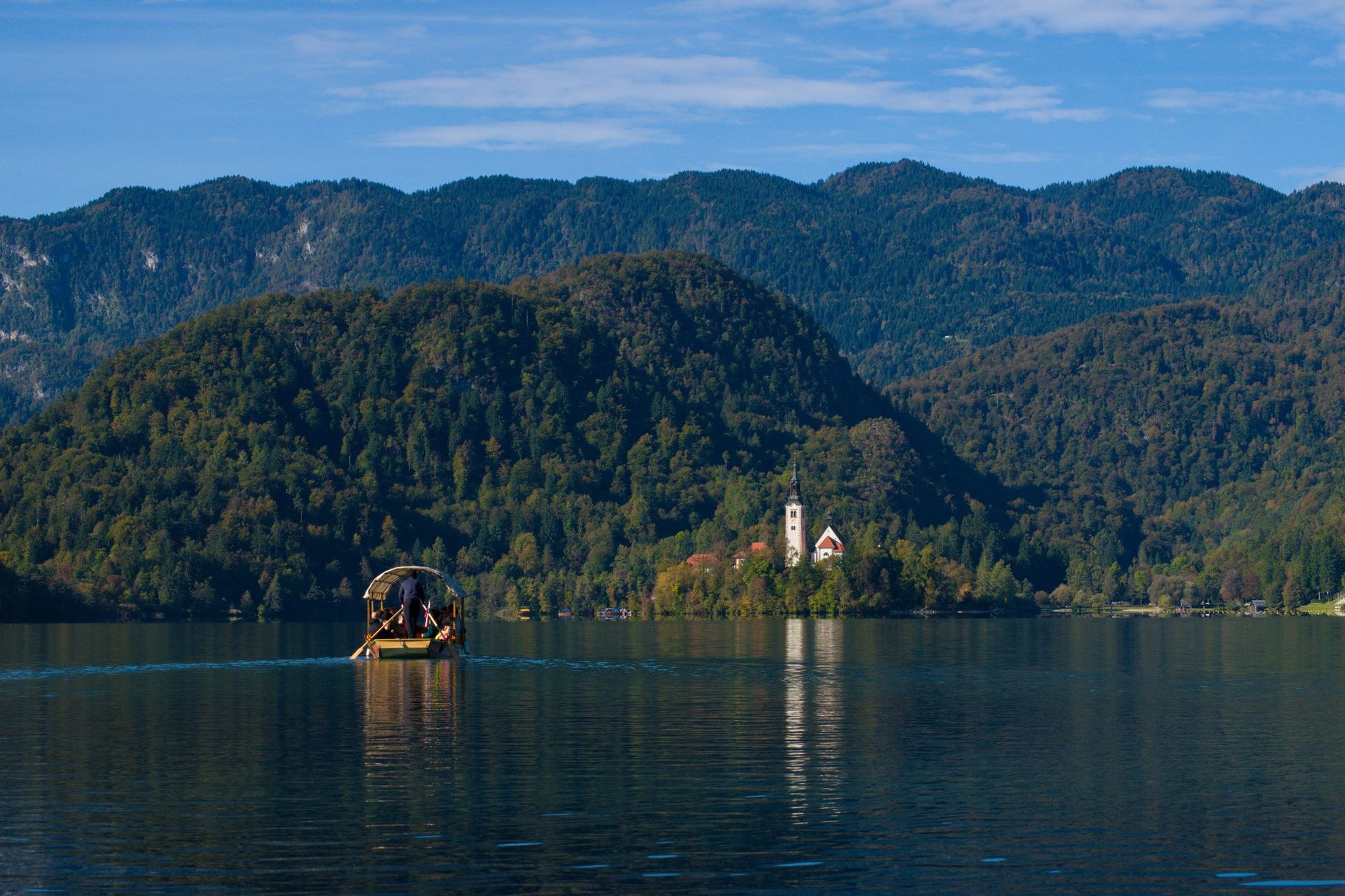 Traditional wooden flat-bottomed pletna oar boat moored along the quiet wooded shores of Lake Bled