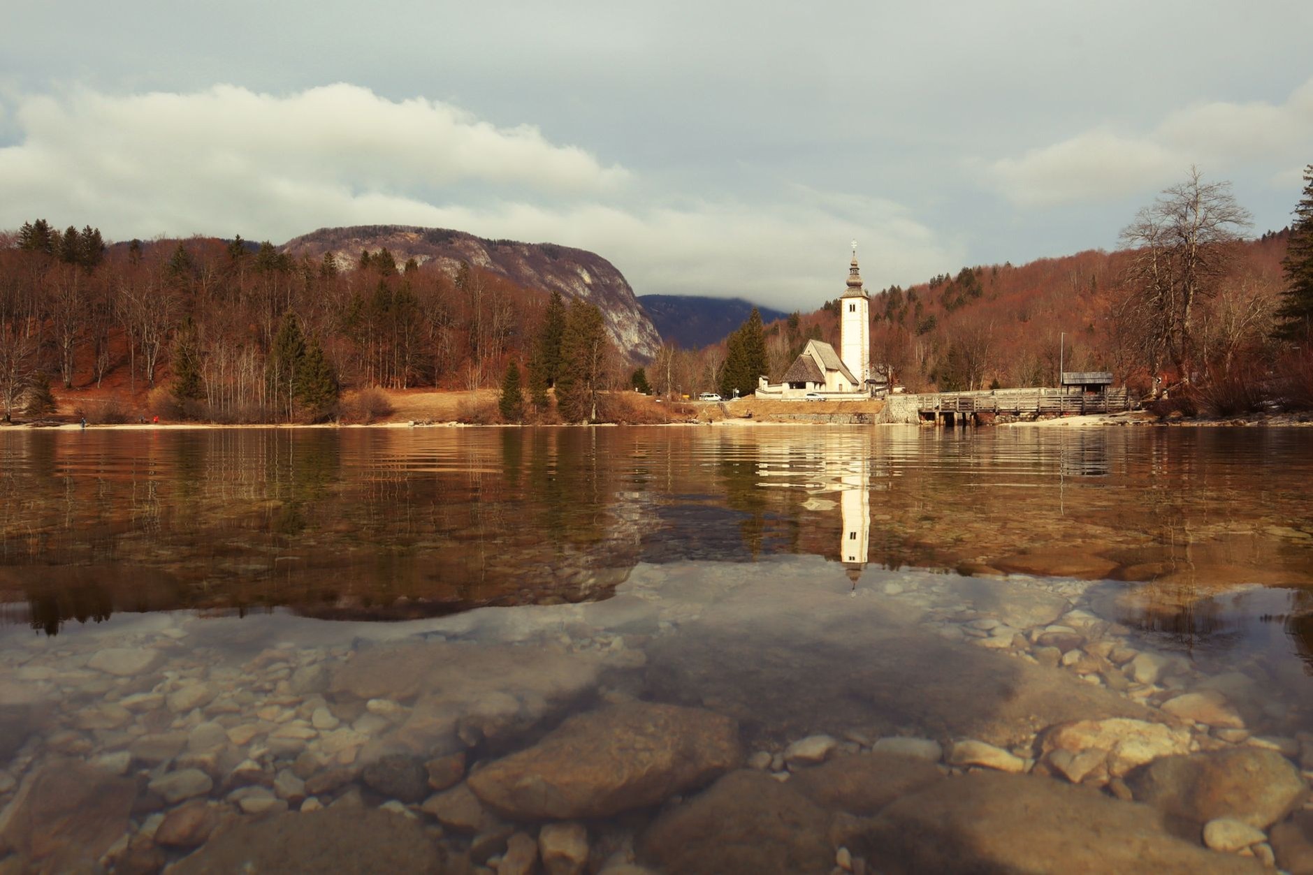 Glacial waters of Lake Bohinj reflecting the towering limestone peaks of the Julian Alps inside Triglav National Park