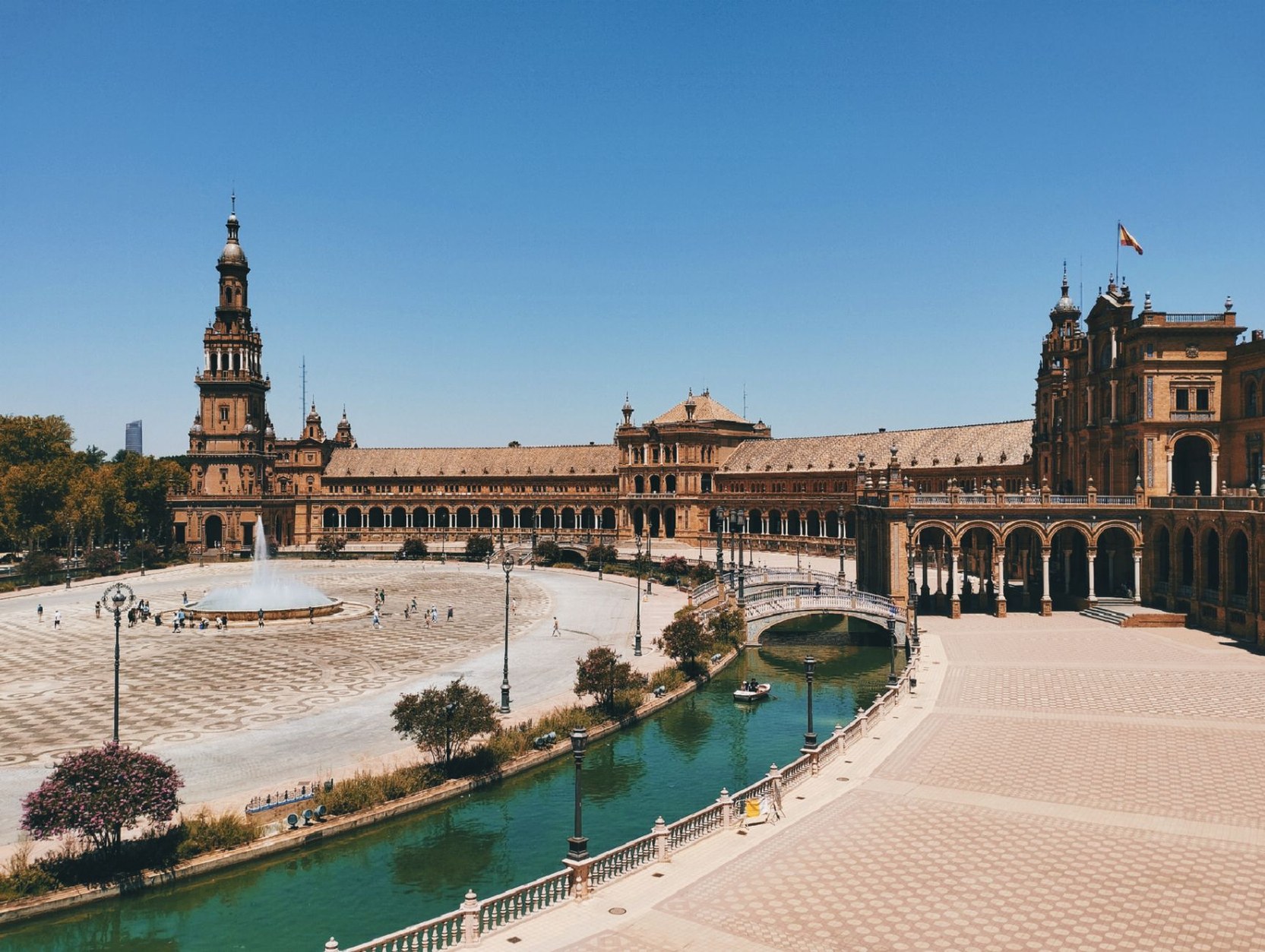 Symmetrical brick colonnades, bridges, and canal of Plaza de España in Seville