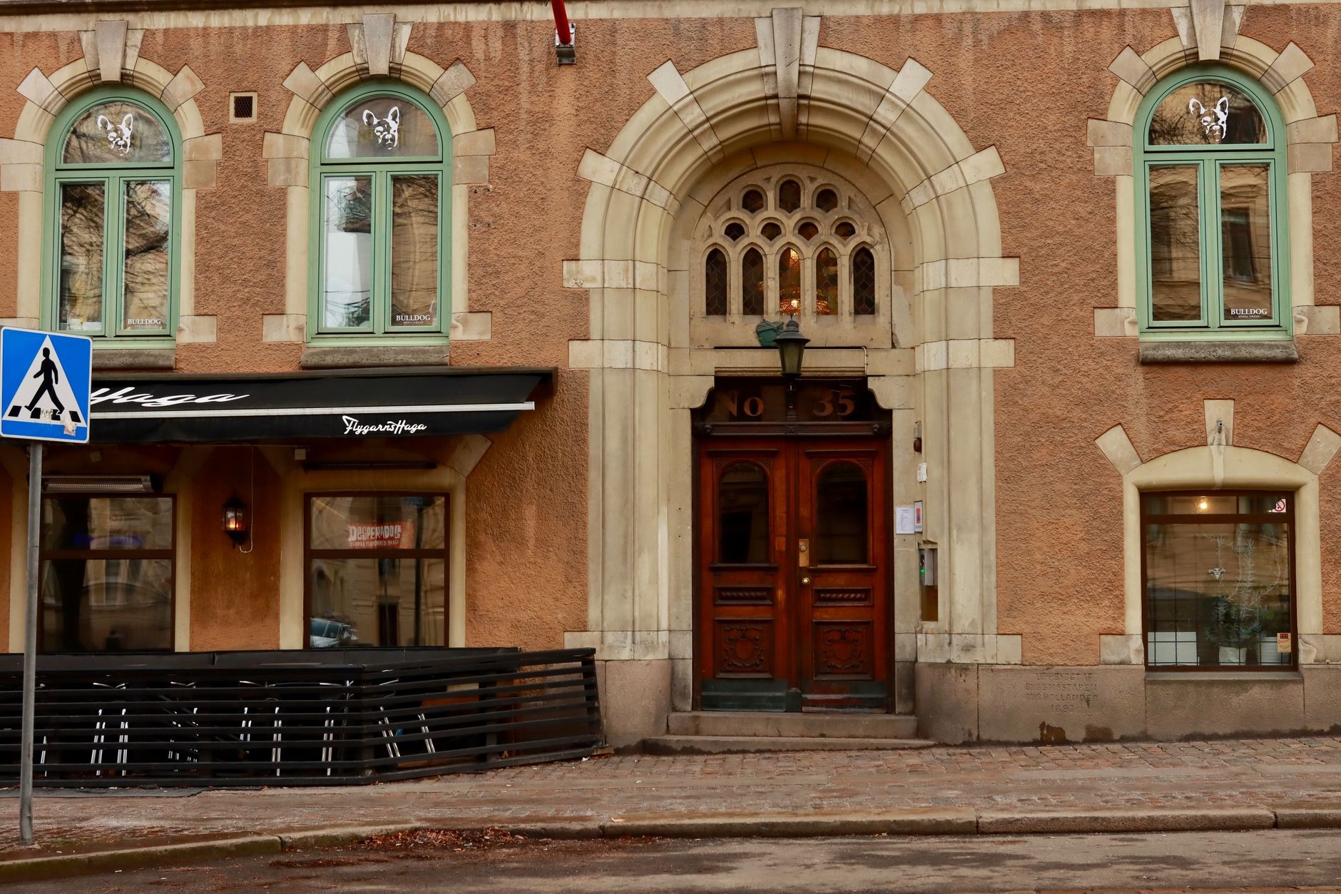 Pedestrian cobblestone street lined with traditional wood-and-brick houses and outdoor cafes in Gothenburg's historic Haga district