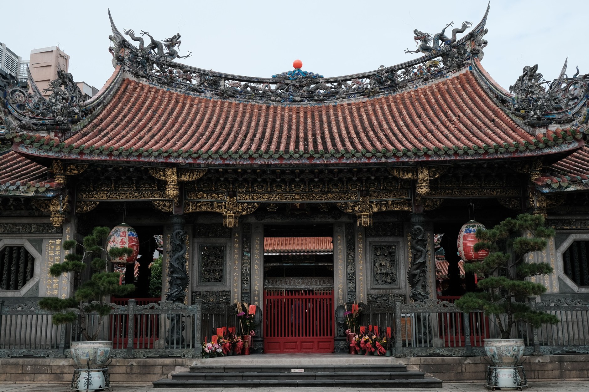 Coiled incense smoke and ornate dragon roof carvings at Longshan Temple in Taipei