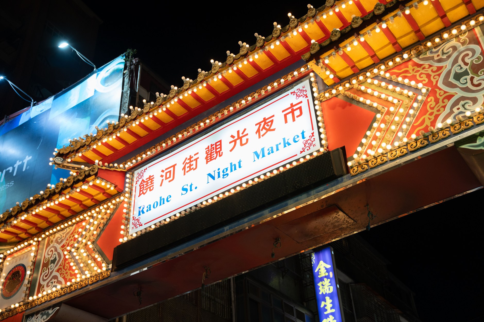 Vibrant neon-lit stalls and crowds at Raohe Night Market in Taipei