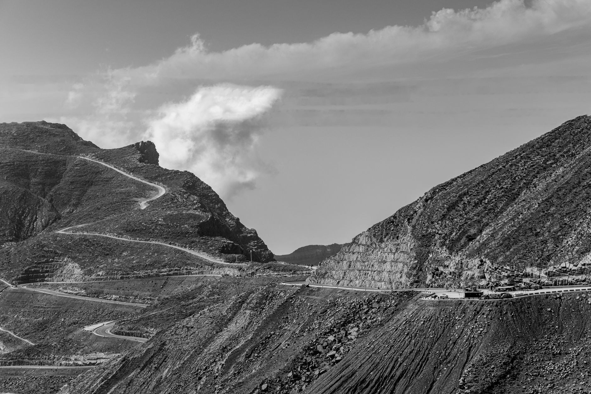 A winding asphalt mountain highway climbing through stark rocky gorges and high elevation passes