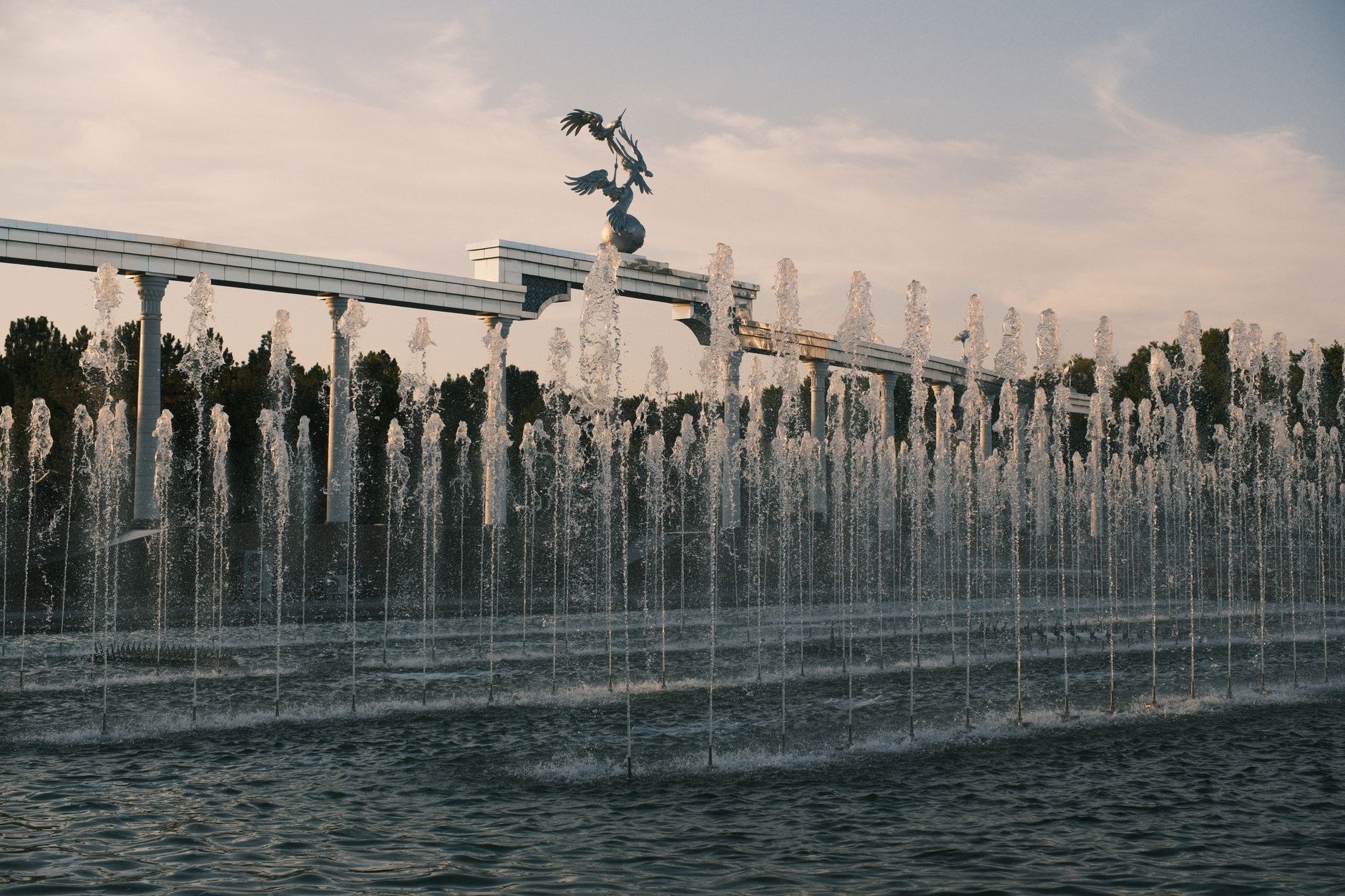 The monumental golden arch and bronze statue of Ismail Somoni surrounded by fountains in central Dushanbe