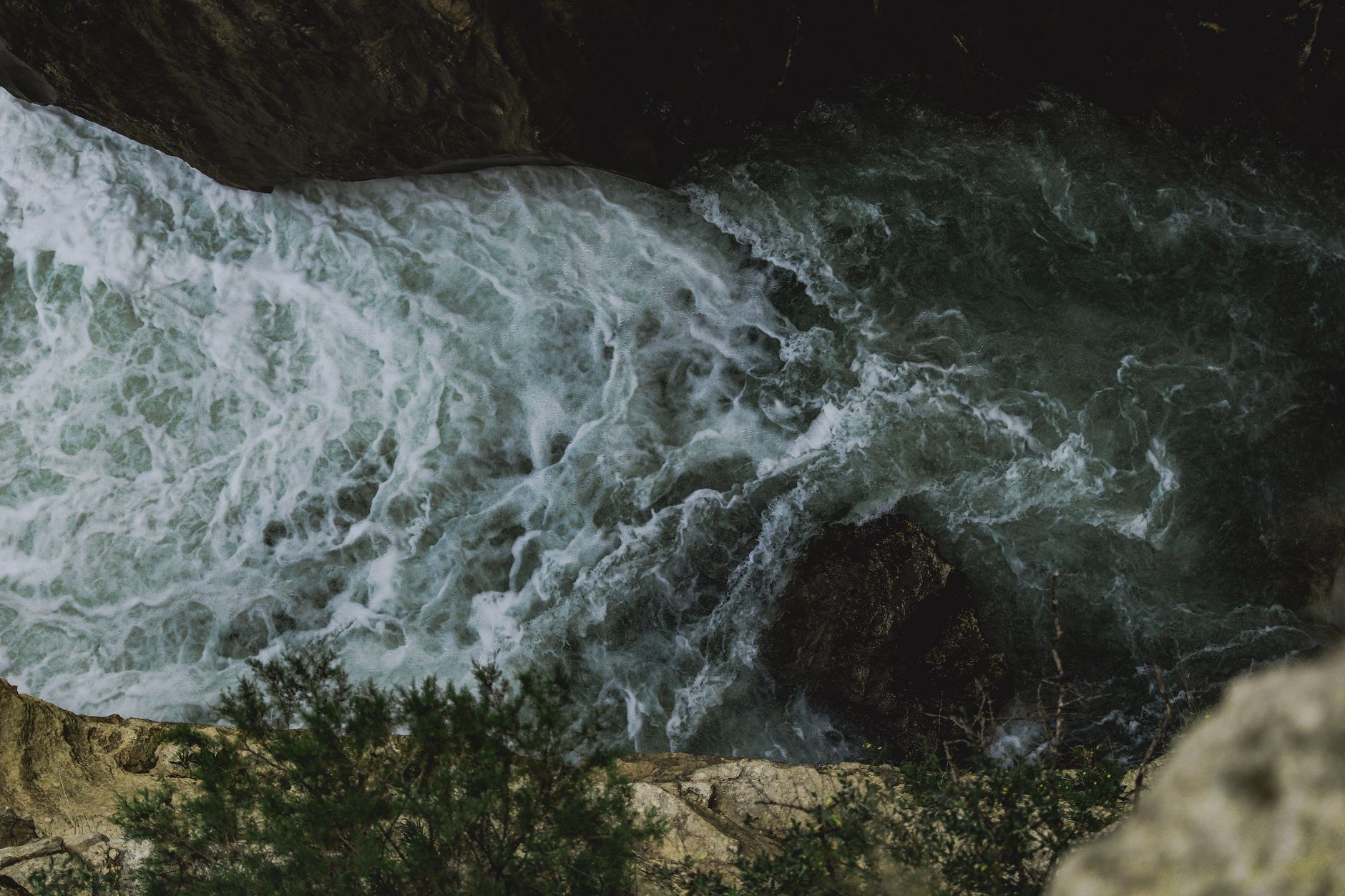 A powerful glacial torrent plunging forty meters through a narrow vertical rock gorge into mist