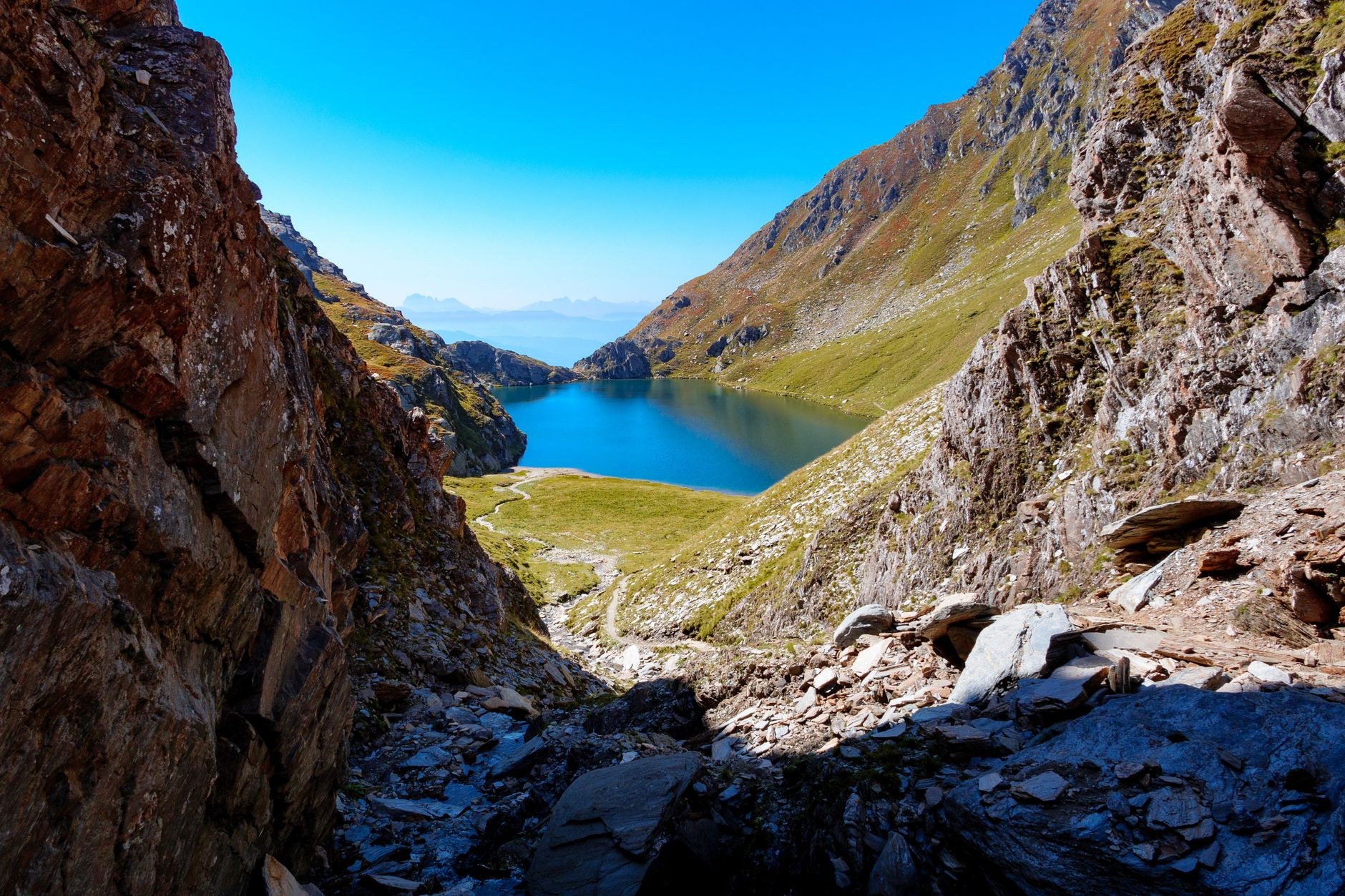Deep indigo and turquoise mountain lake waters framed by steep scree slopes and rugged canyon walls