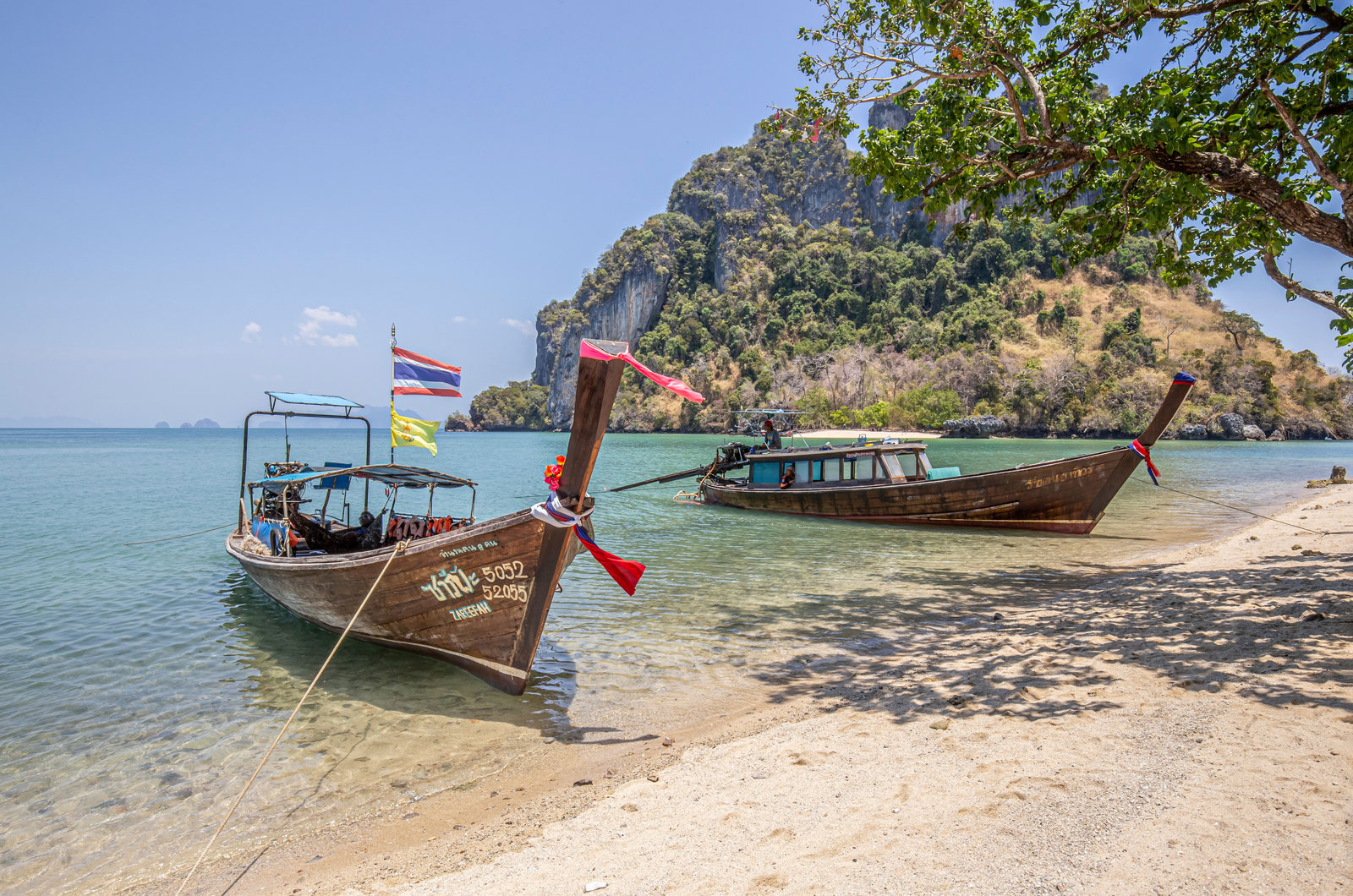 Wooden longtail boats on a sandy beach near Ao Nang in Krabi