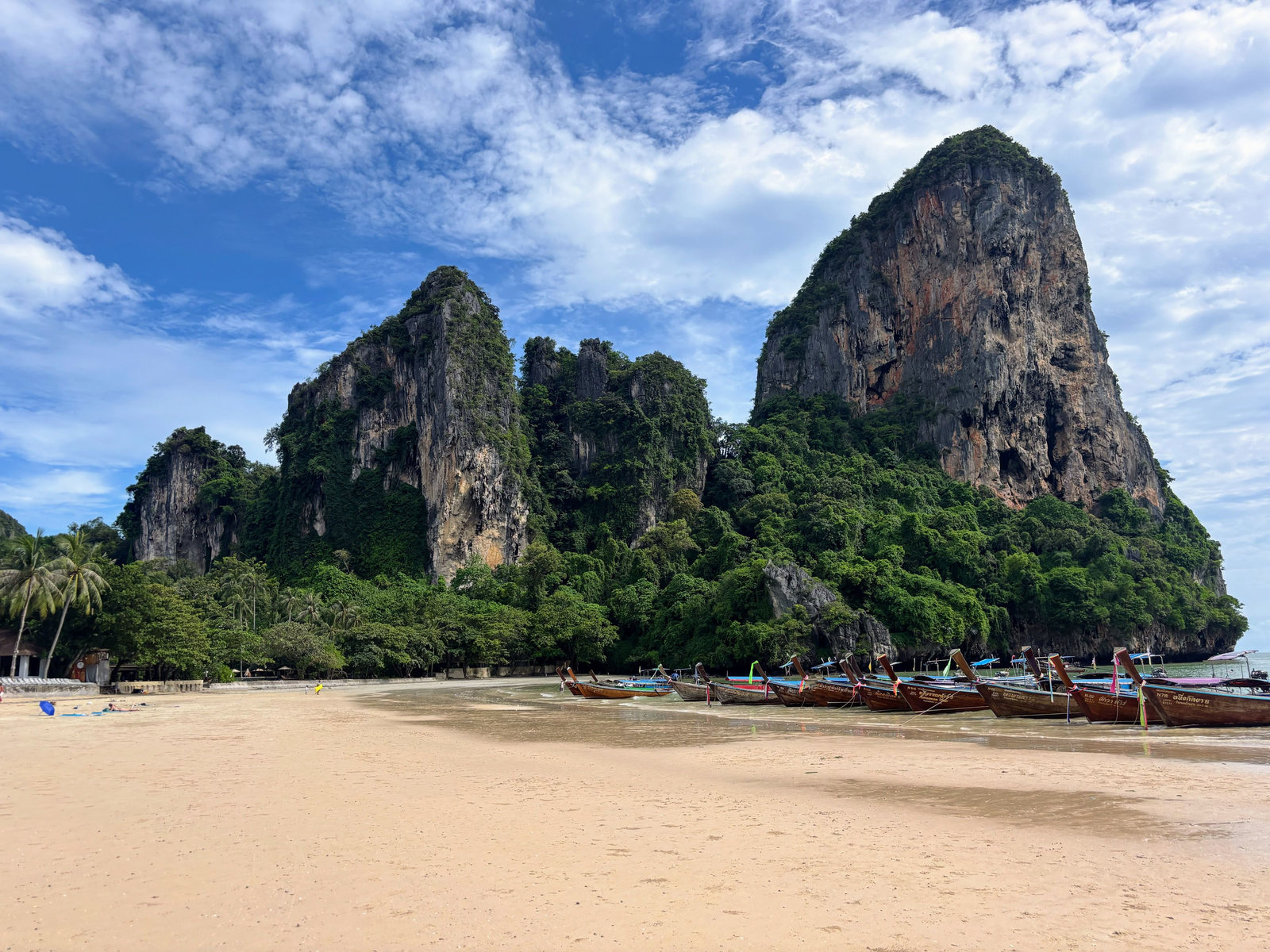 Longtail boats beneath limestone cliffs at Railay Beach in Krabi