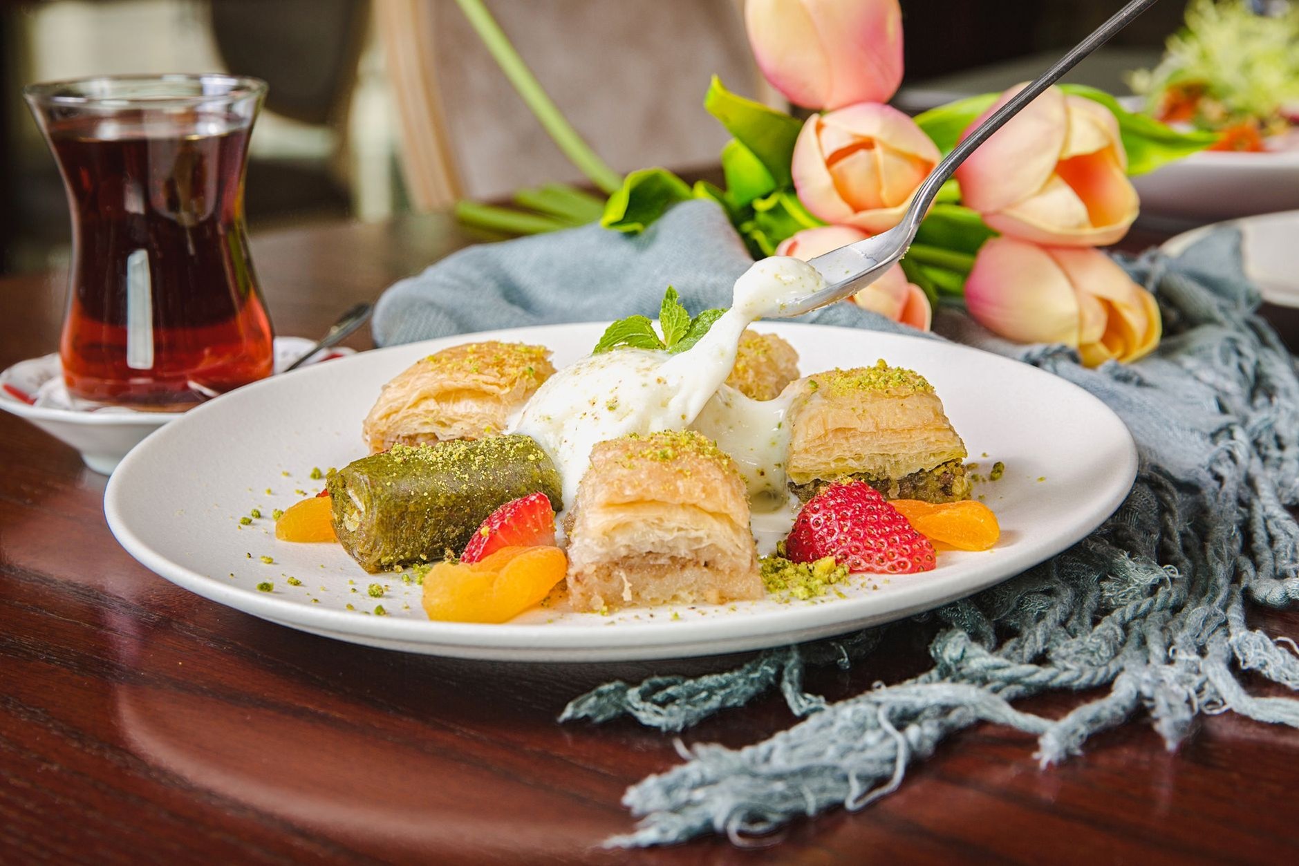Traditional tulip-shaped glass of black Turkish tea served with sweet pistachio baklava