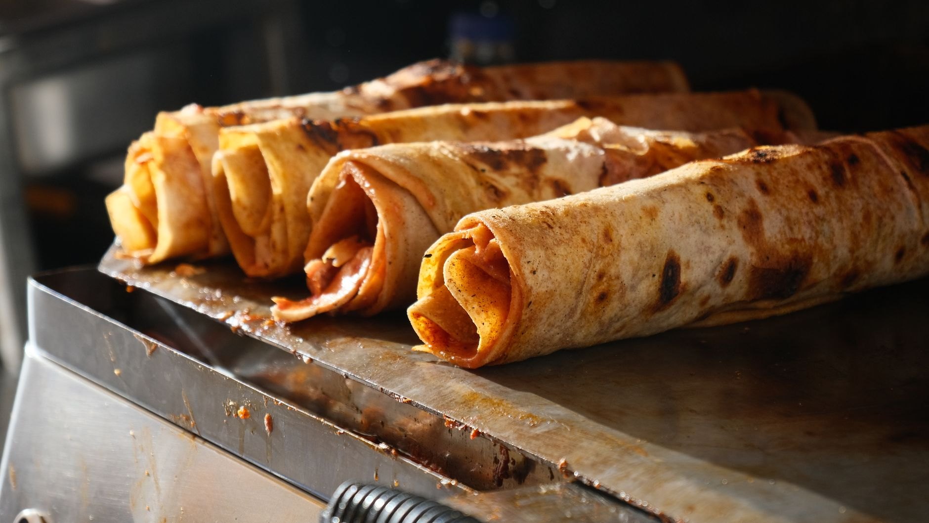 Warm rolled chapati filled with fried egg omelette, diced tomatoes, and red onions prepared fresh on a street griddle