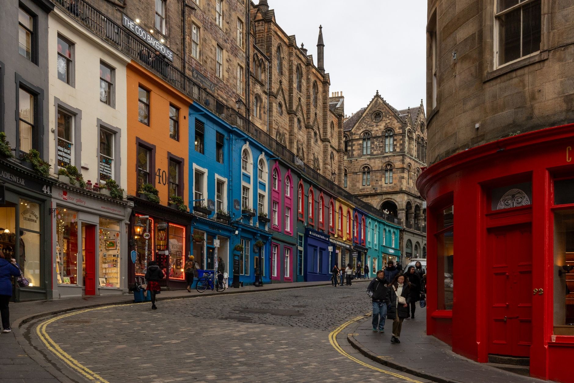 Curving cobblestone incline and brightly painted shopfronts of Victoria Street in Edinburgh