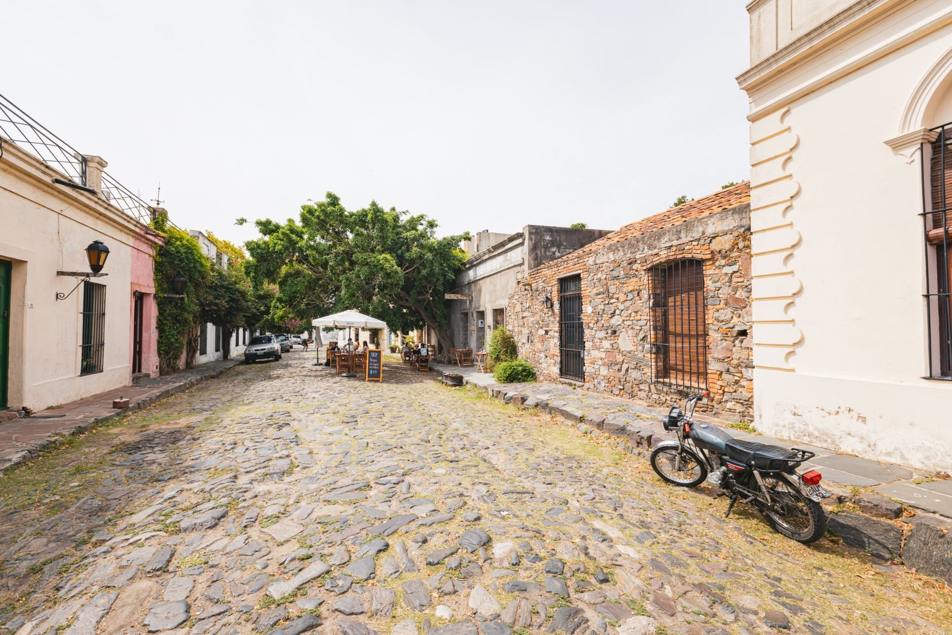 Narrow cobblestone street flanked by colorful colonial Portuguese stone cottages with tiled roofs in Colonia del Sacramento