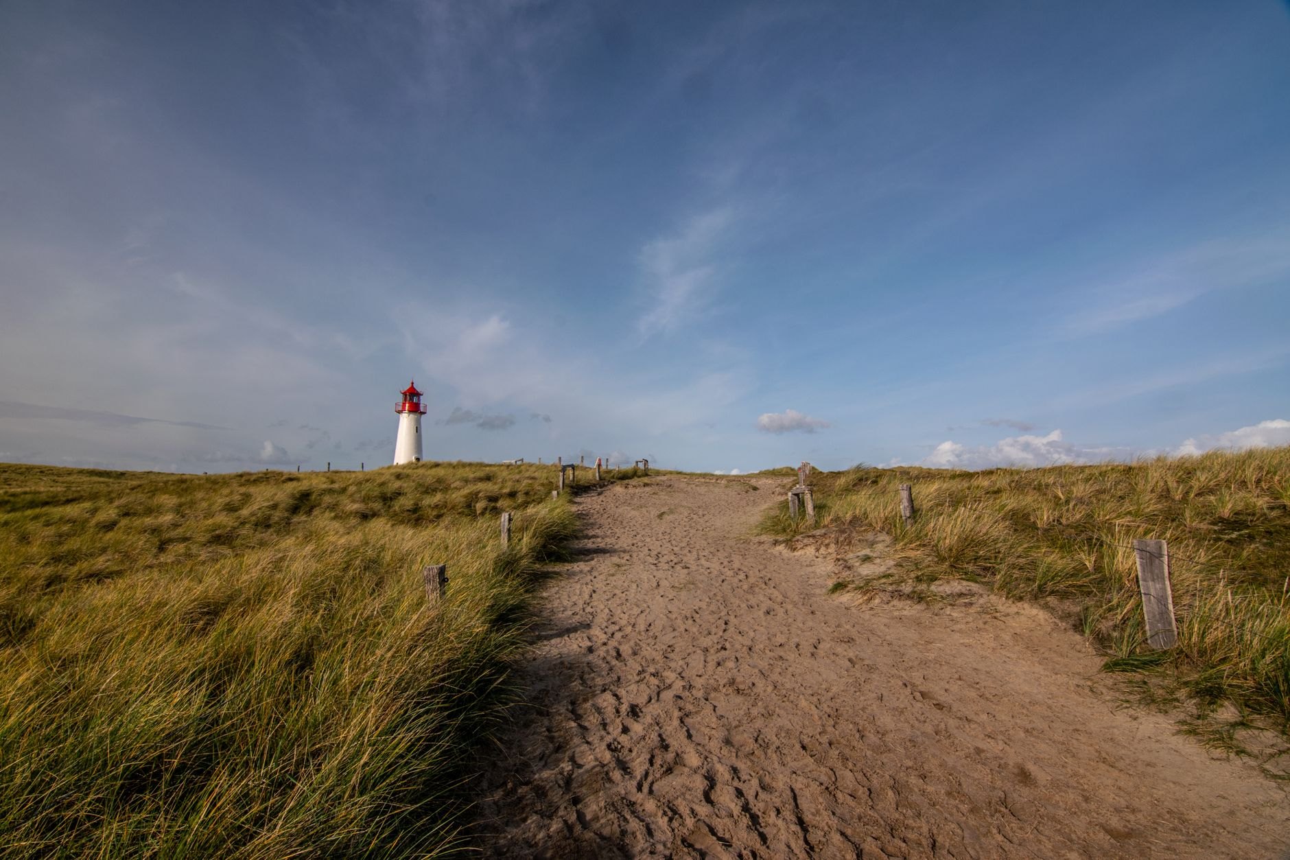 Stone lighthouse standing on a grassy headland beside rolling ocean dunes and breaking Atlantic waves in José Ignacio