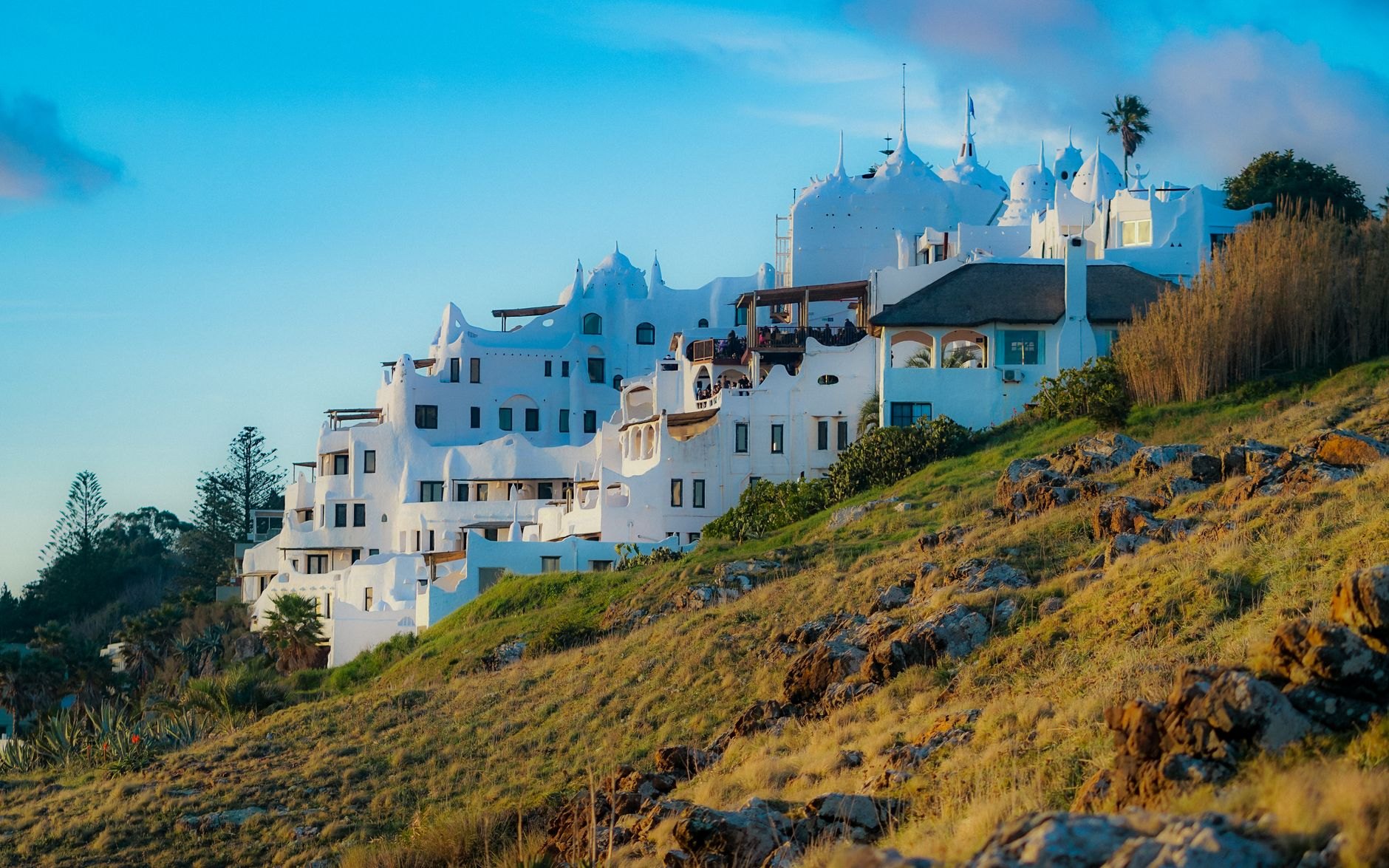 Sprawling white sculptural cliffside complex of Casapueblo cascading down rocky cliffs into the blue Atlantic Ocean