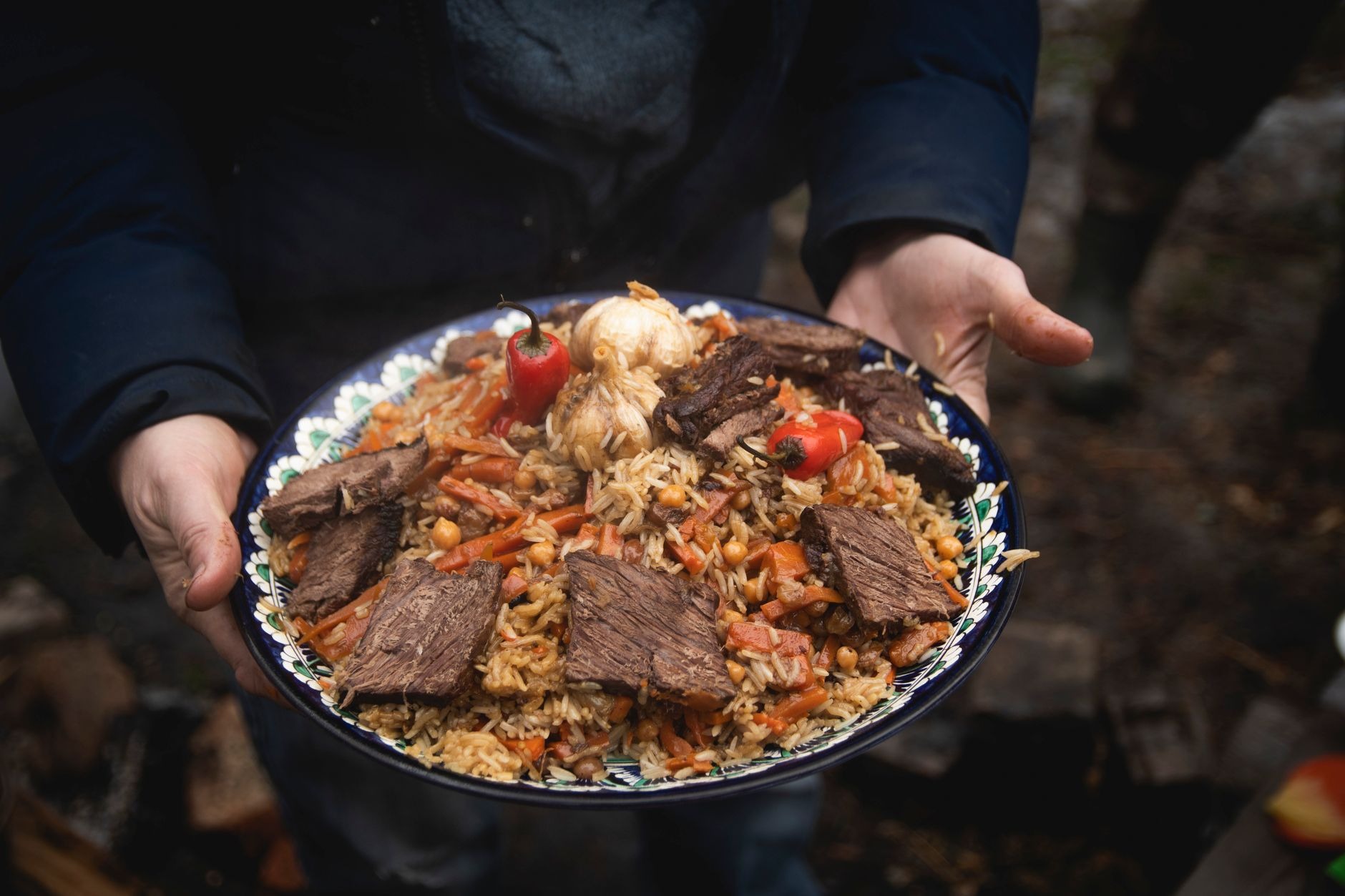 Fragrant traditional Uzbek plov pilaf with tender lamb, golden rice, yellow carrots, and whole garlic simmered in a cast-iron kazan