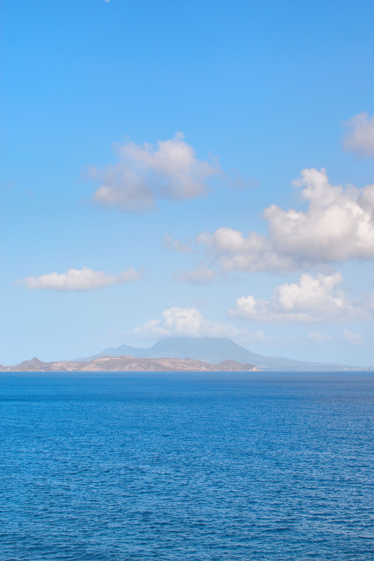 Tranquil Caribbean Sea waters with the misty green slopes of Nevis Peak in the distance