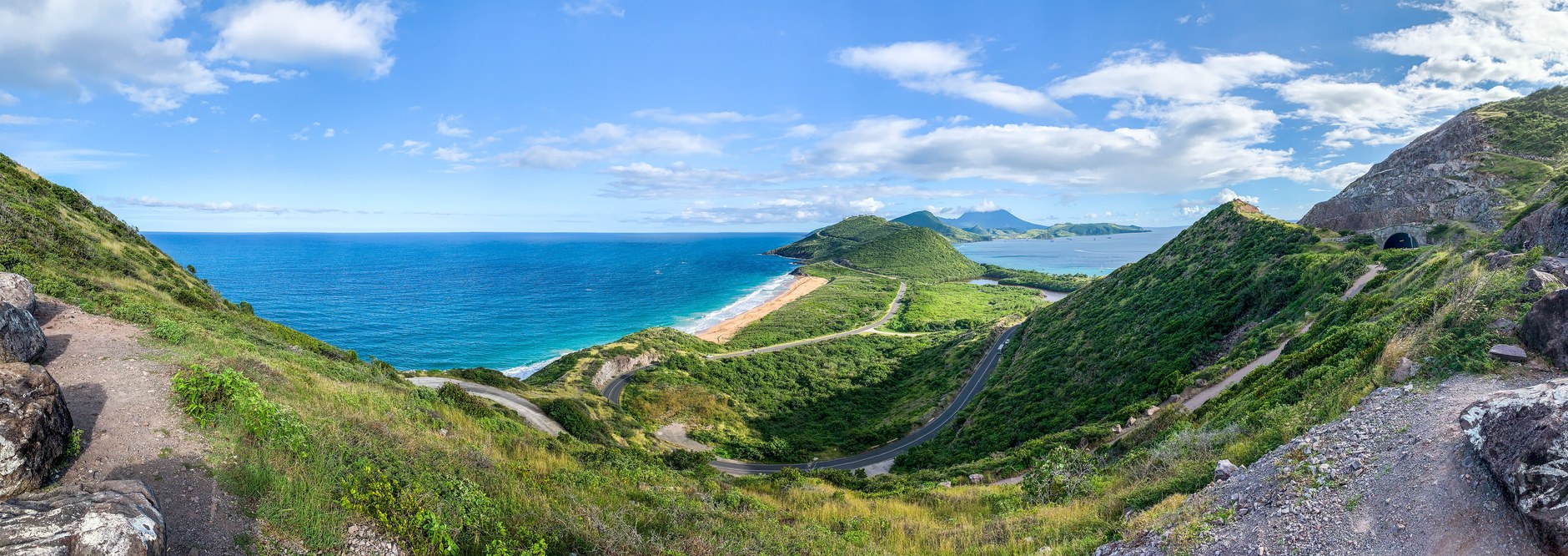 Expansive green volcanic slopes and coastal cliffs falling into the deep blue Caribbean ocean