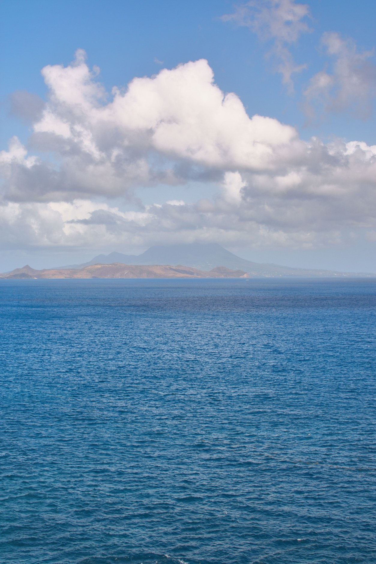The volcanic cone of Nevis Peak rising above the calm turquoise waters of The Narrows strait