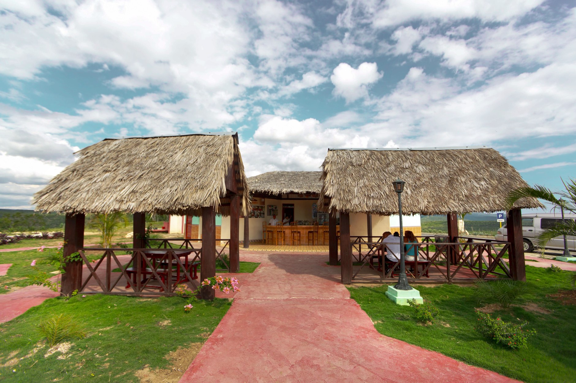 Traditional open wooden pavilion with thatched roof set within a tidy green village garden