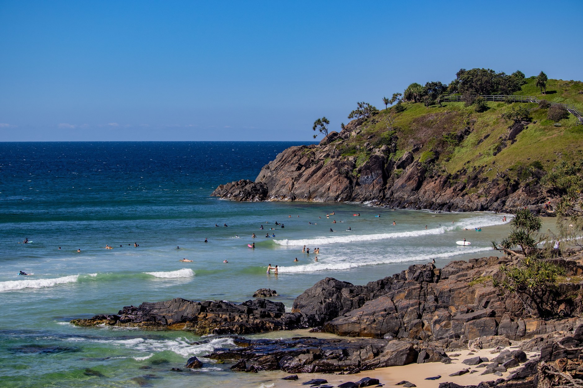Curved sandy beach and rolling Atlantic surf framed by forested headlands at Bureh Beach