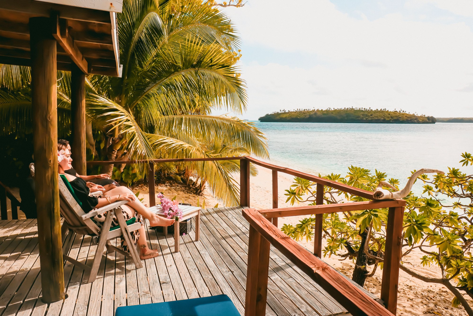 Wooden terrace and palm trees overlooking calm turquoise ocean waters