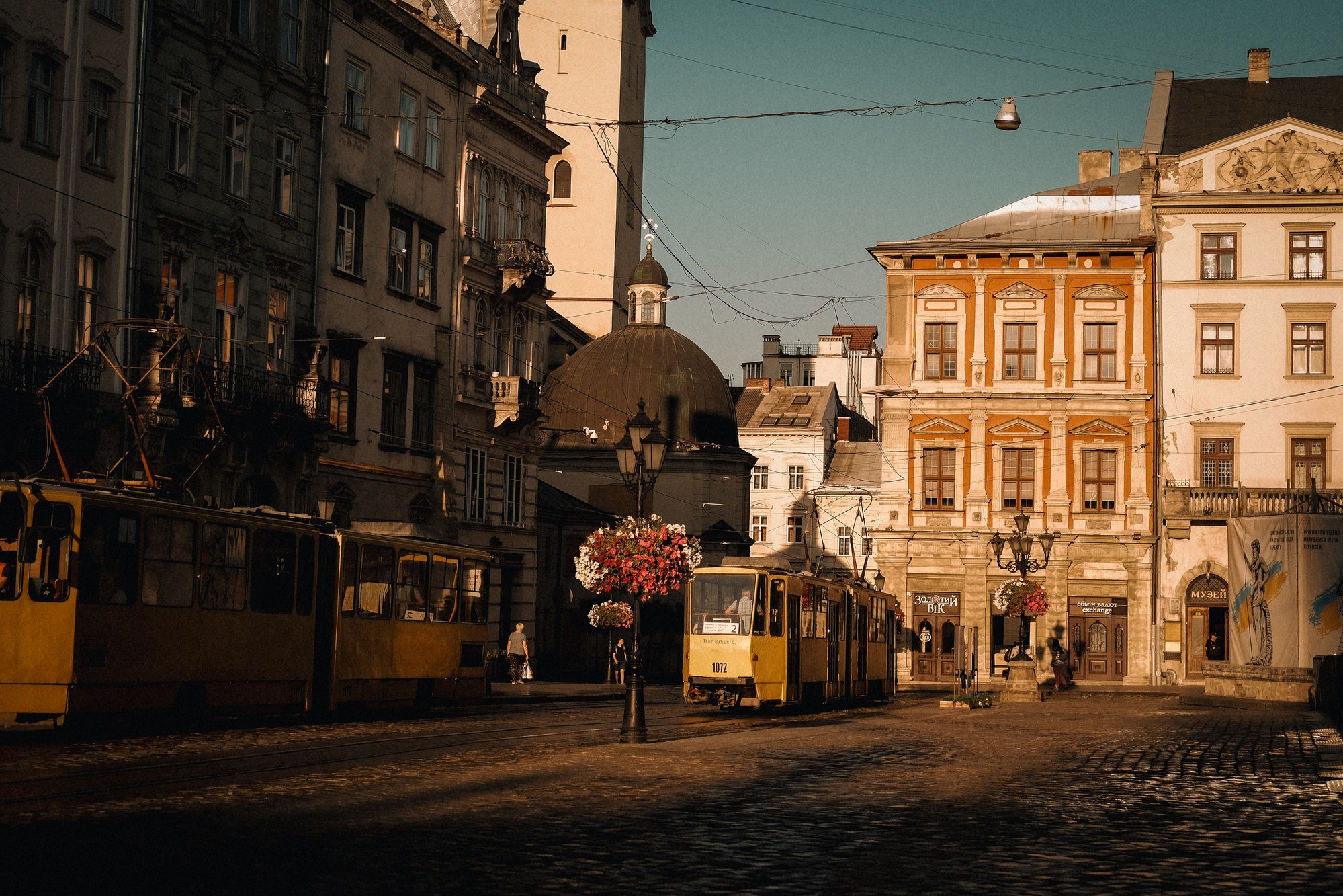 Yellow municipal tram moving along cobblestone streets flanked by historic European architecture in Lviv