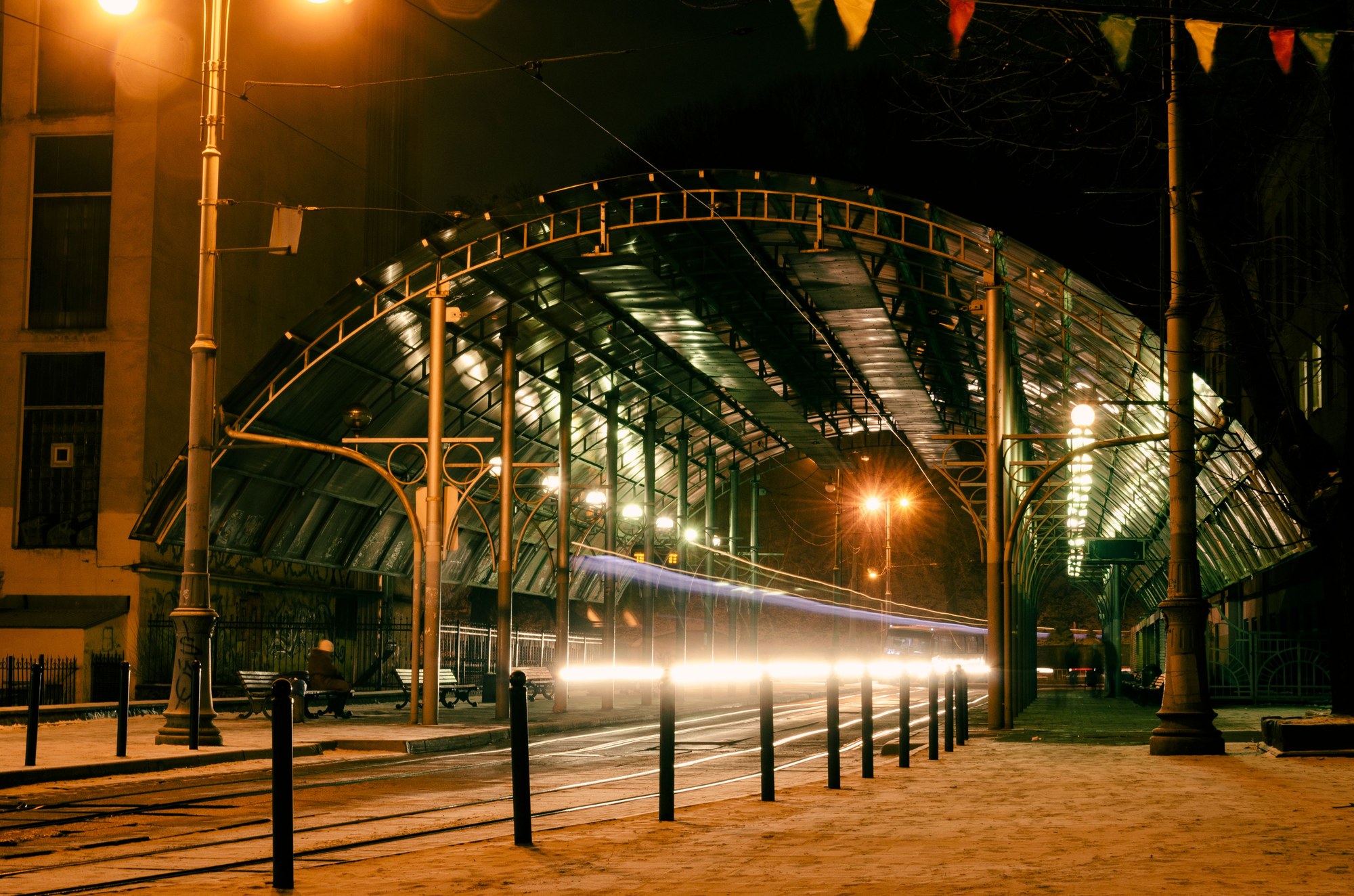Illuminated passenger train departing a historic railway station at night in Ukraine