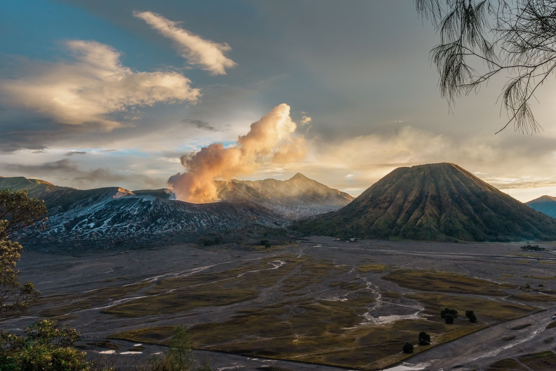 Dramatic desolate black volcanic ash plains surrounding an active smoking volcano cone