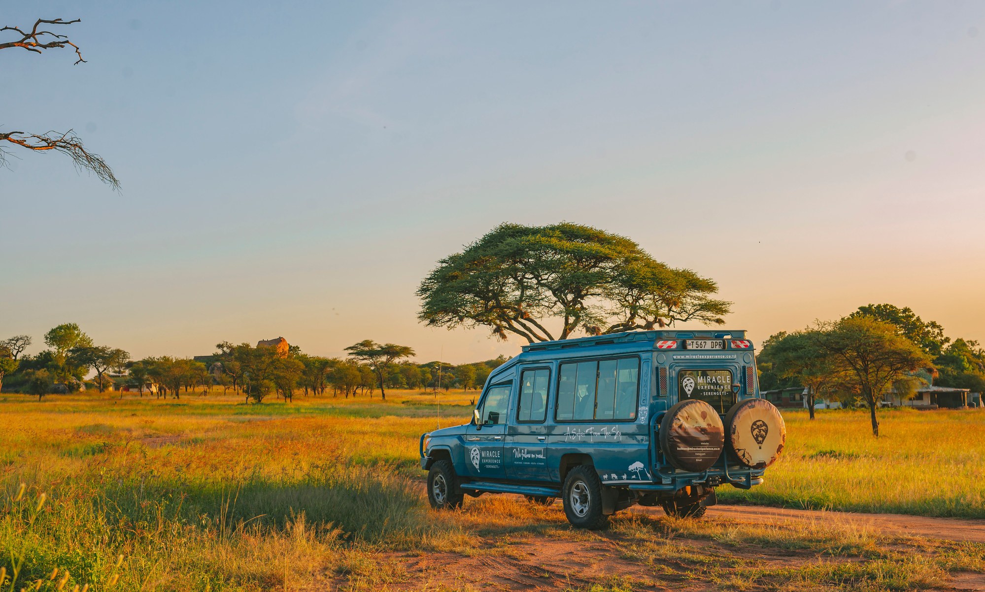 Safari 4x4 jeep parked on the open savanna during golden sunset hour