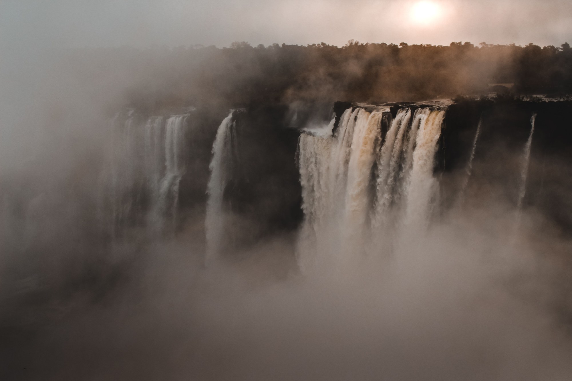 Massive wall of falling water enveloped by rising mist and spray in rocky chasm