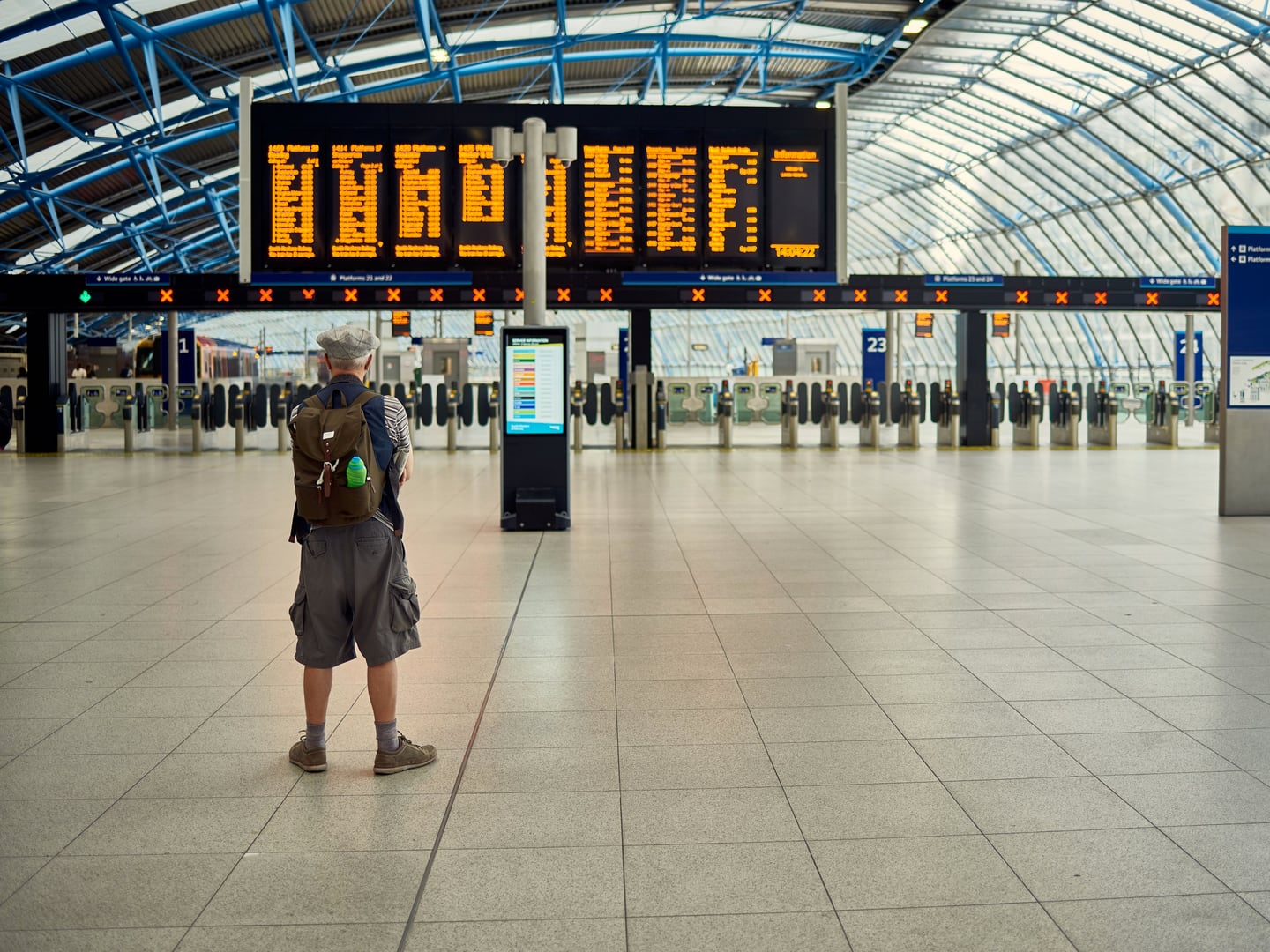 A traveller with a backpack viewing a departure board in a modern station terminal.