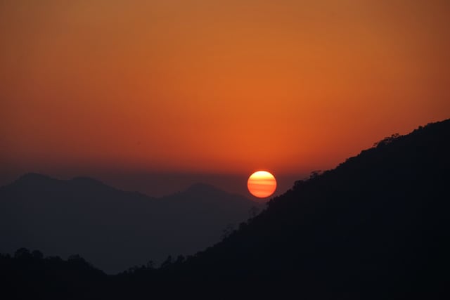 A breathtaking sunrise over the mountains in Deothang, Bhutan, with vivid orange tones.