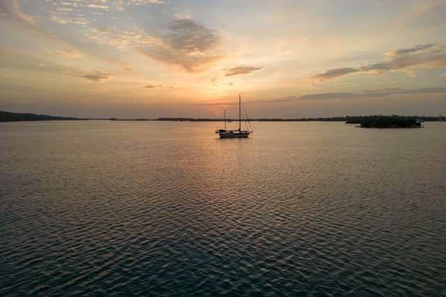 A sailboat peacefully drifts at sunset near Barú, Colombia, reflecting a serene evening vibe.