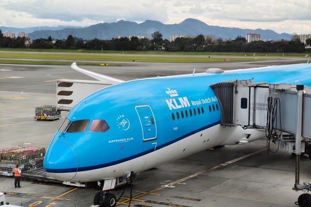 KLM airplane at boarding gate in Bogotá airport with mountain backdrop, ready for departure.