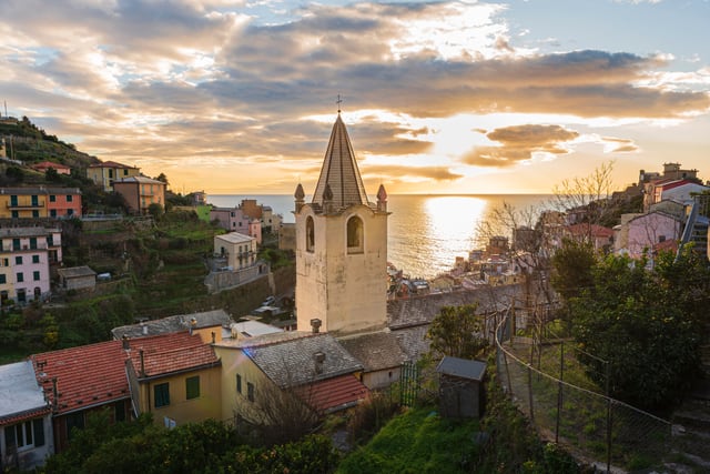 Warm evening light on a hillside town above the sea in Italy.