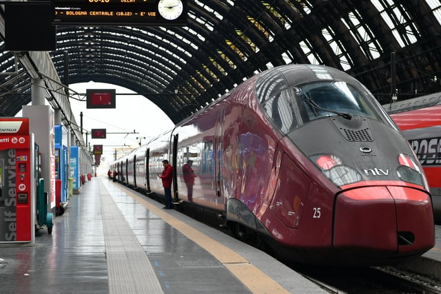 A high-speed train awaits passengers under the grand arched iron-and-glass vault of Milano Centrale station in Italy.