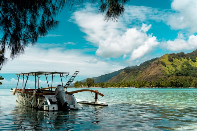 A picturesque scene of a boat resting in the calm waters of Moorea, French Polynesia, under a bright blue sky.